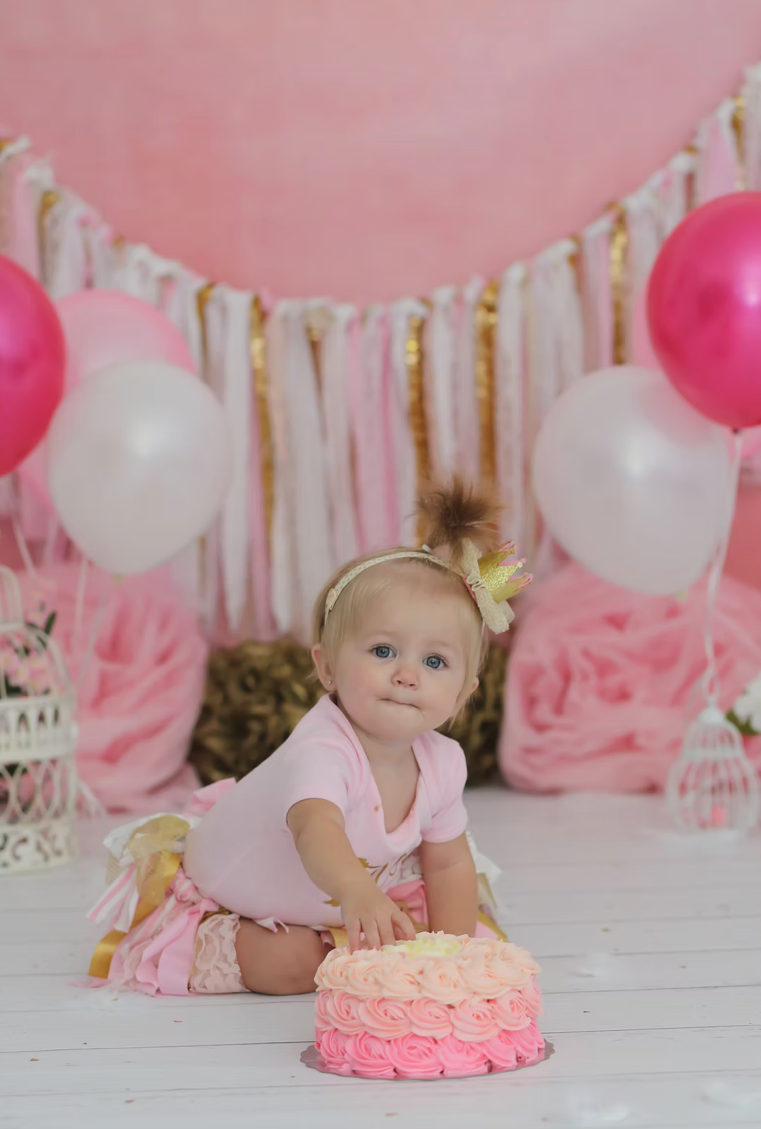 Pink and white first birthday setup with ombre cake and balloon decorations.