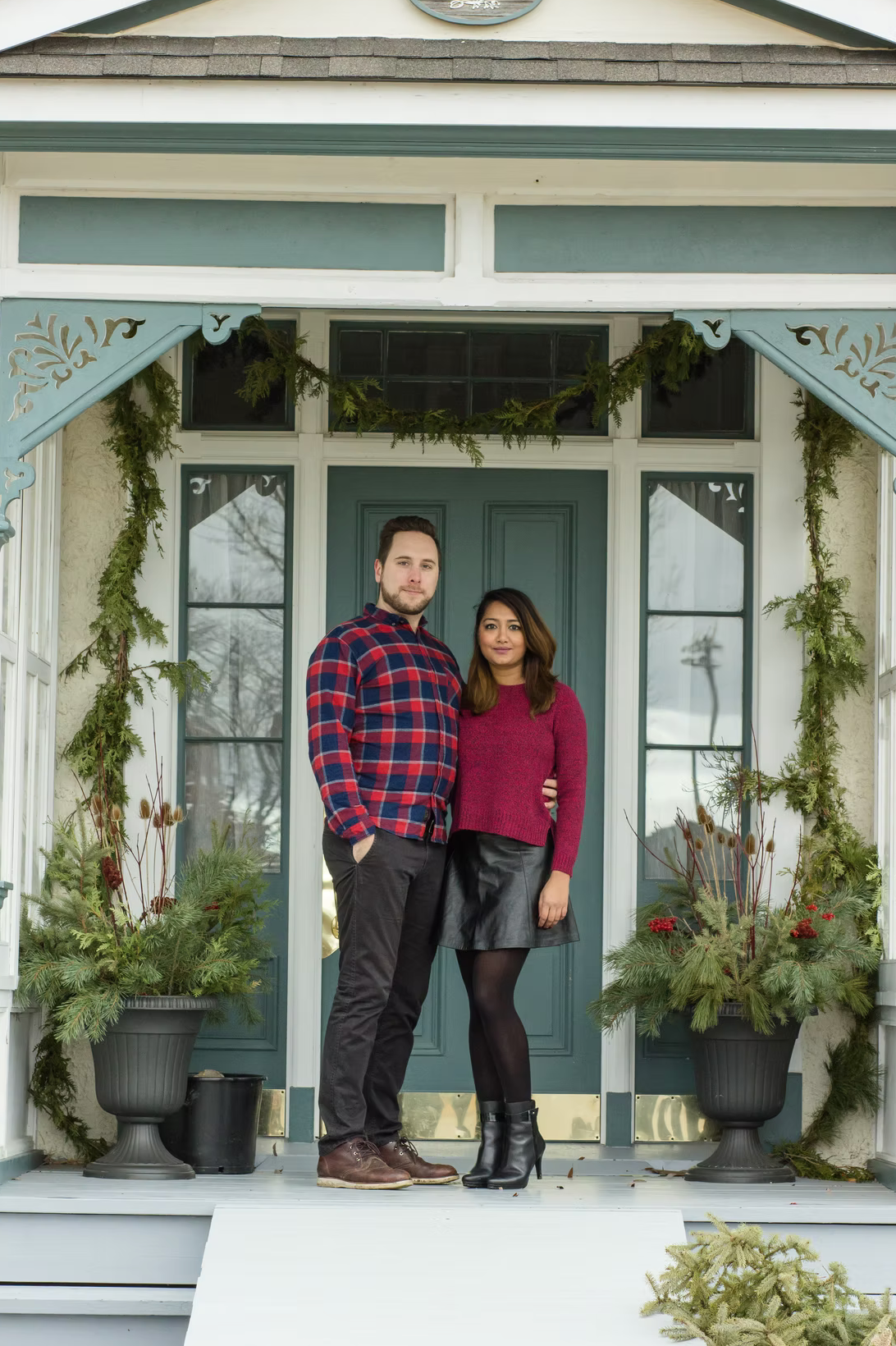 Holiday portraits on front porch decorated with evergreen garland and winter decor.