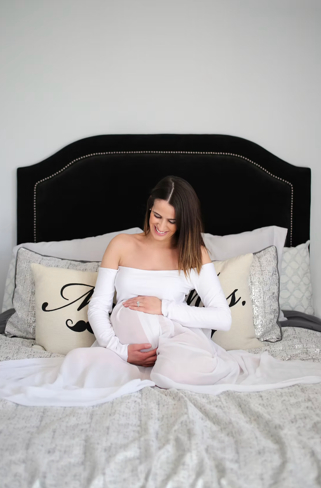 A cozy bedroom scene with white bedding and a black upholstered headboard.