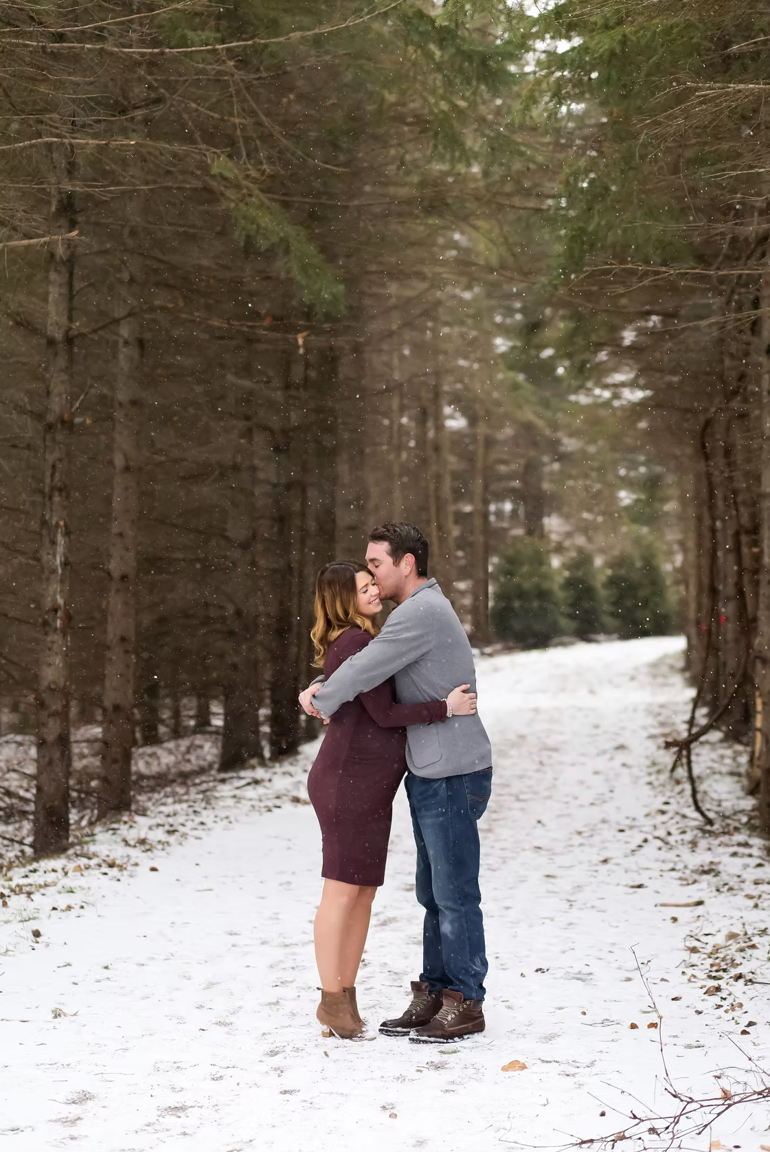 Romantic winter engagement photos in a snow-covered forest setting.