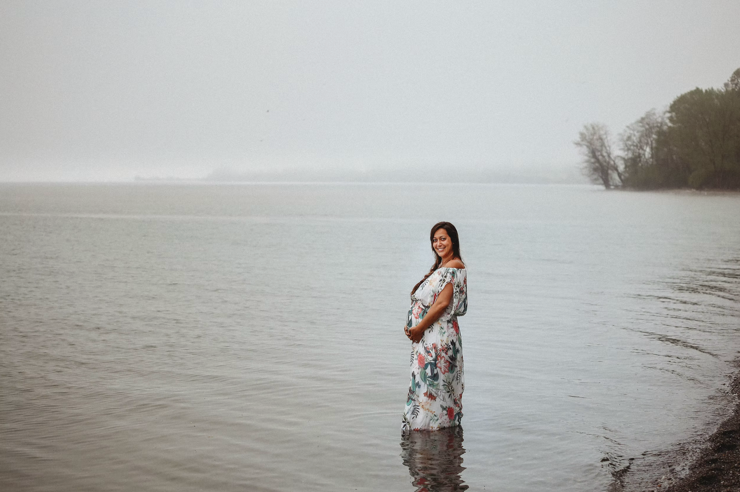 A waterside maternity photo session with soft, dreamy lighting.