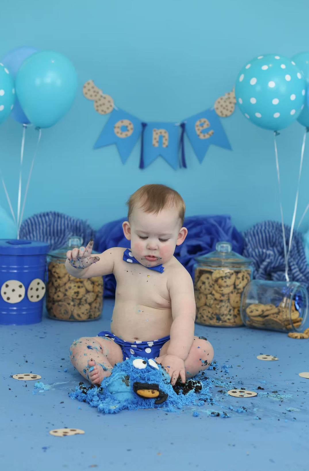 Cookie monster themed cake smash with blue balloons and party decorations.