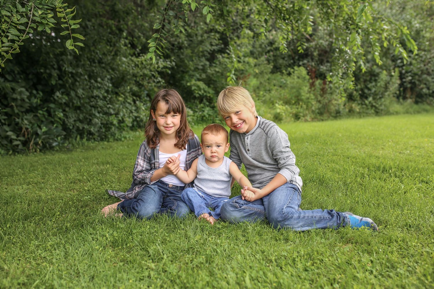 Family lying together on green grass during an outdoor photo session.