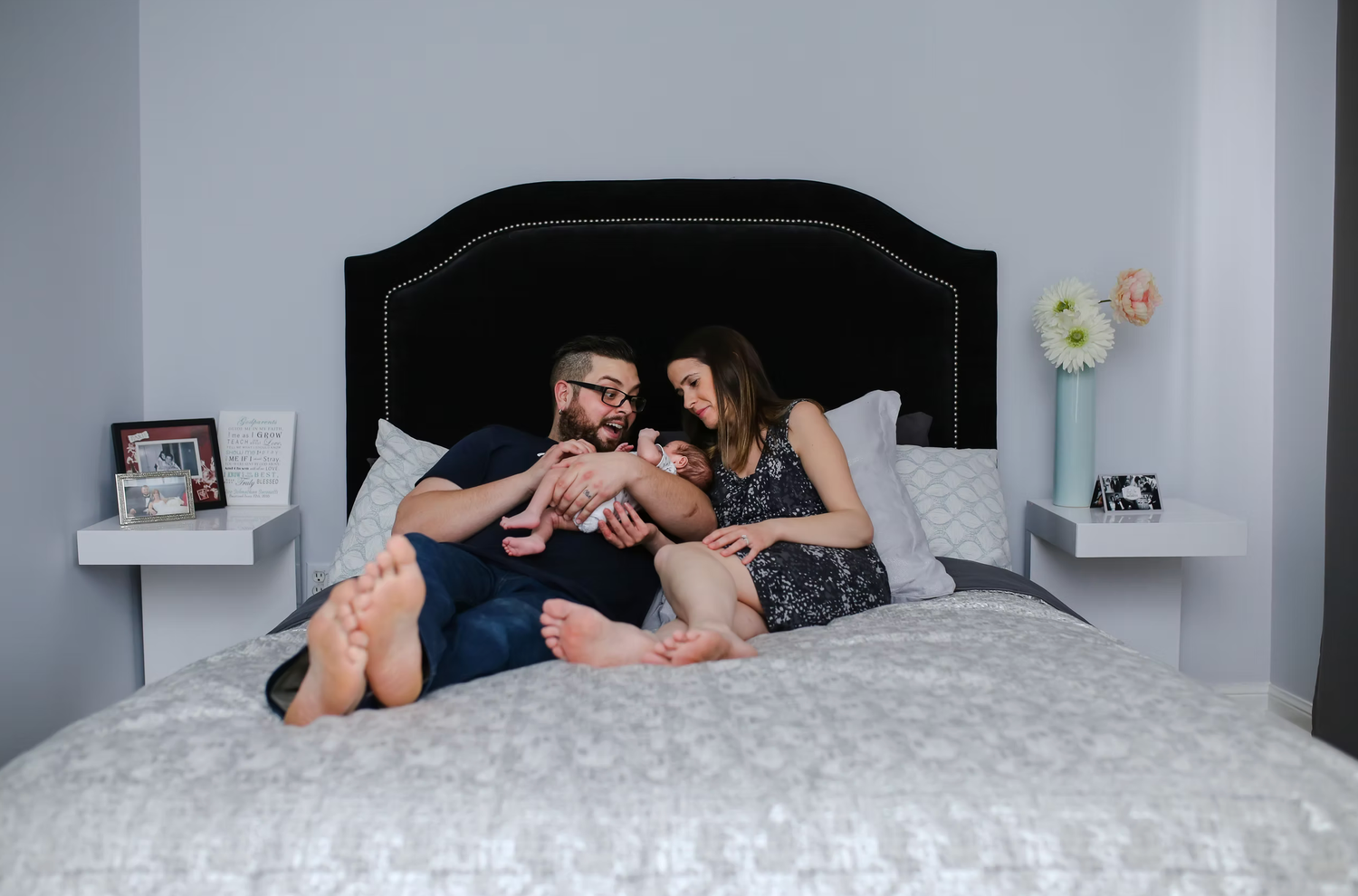 Couple lying together on white bedding during an intimate lifestyle photoshoot.