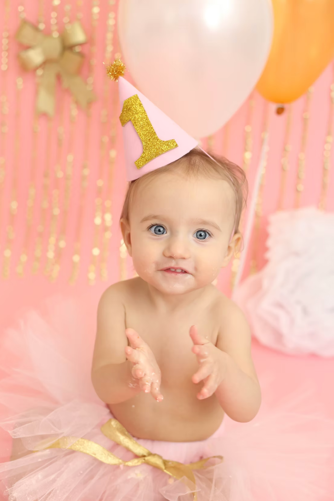 Festive pink and gold first birthday party setup with balloons and sparkly decorations.