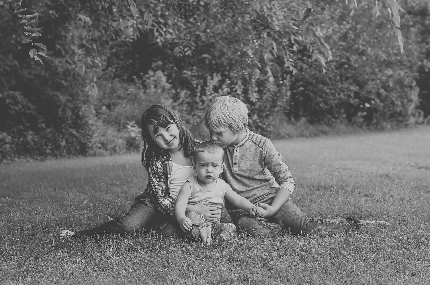 Black and white image of family bonding time on grass outdoors.