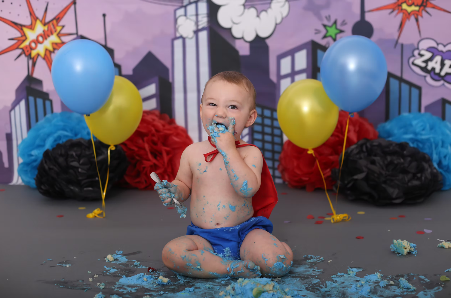 Superhero themed birthday setup with colorful balloons and city backdrop.