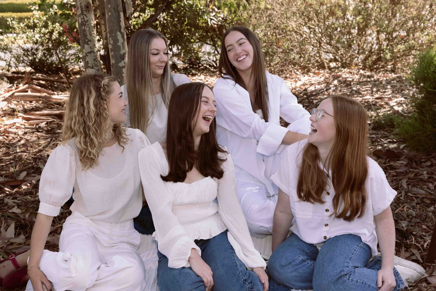 Small team brand photo of 5 women sitting on the garden.