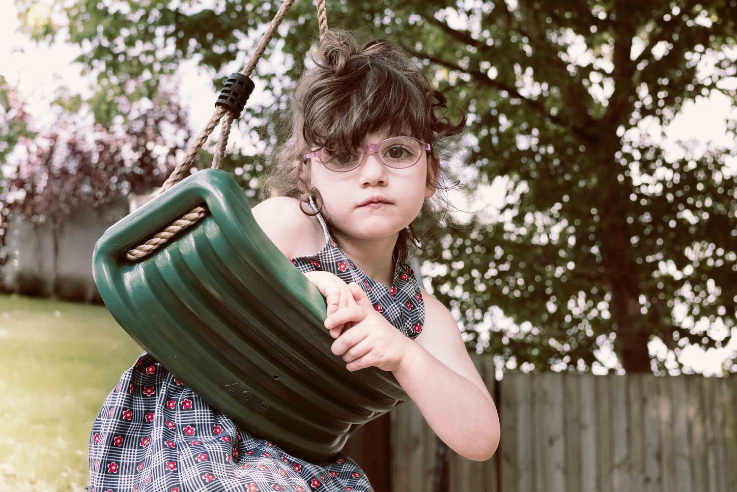 face of young girl on swing gazing at the camera
