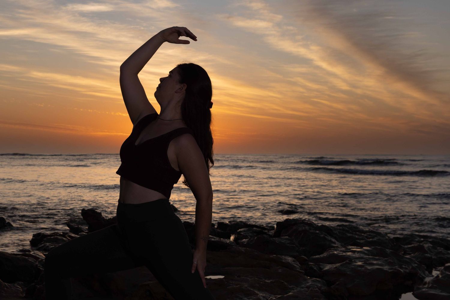 young woman practicing yoga at sunrise at the beach