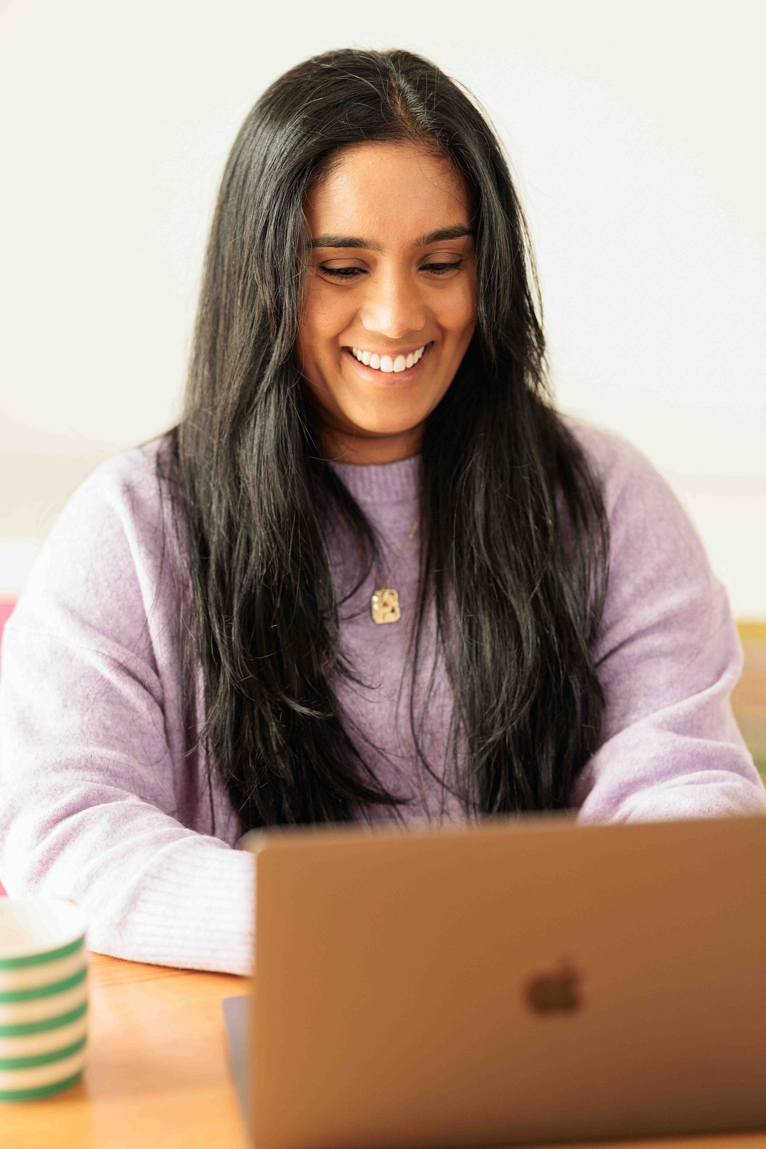 Woman smiling while using a laptop.