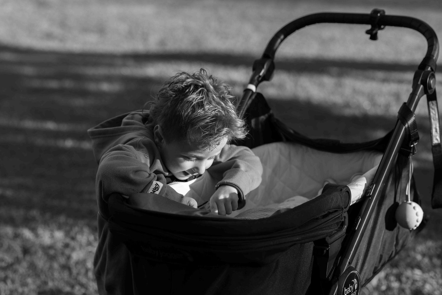 Young boy looking at his sibling in pram. Leigh Ball documentary family photography