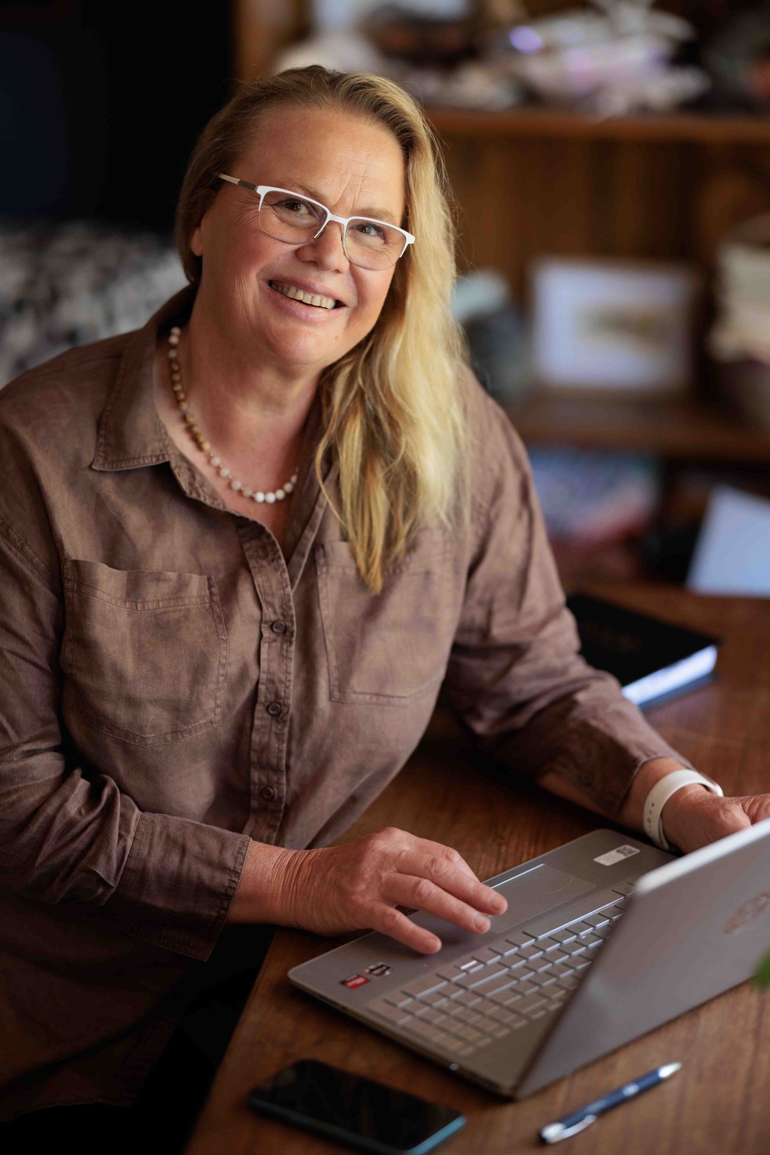 Woman working on a laptop at a wooden desk