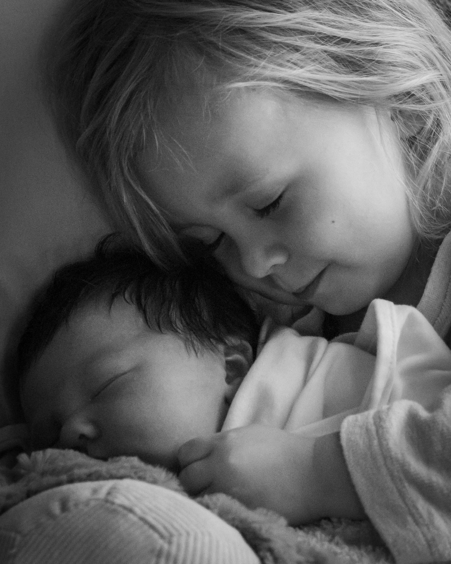 Newborn baby and young child sleeping in black and white photo by Leigh Ball Photography.