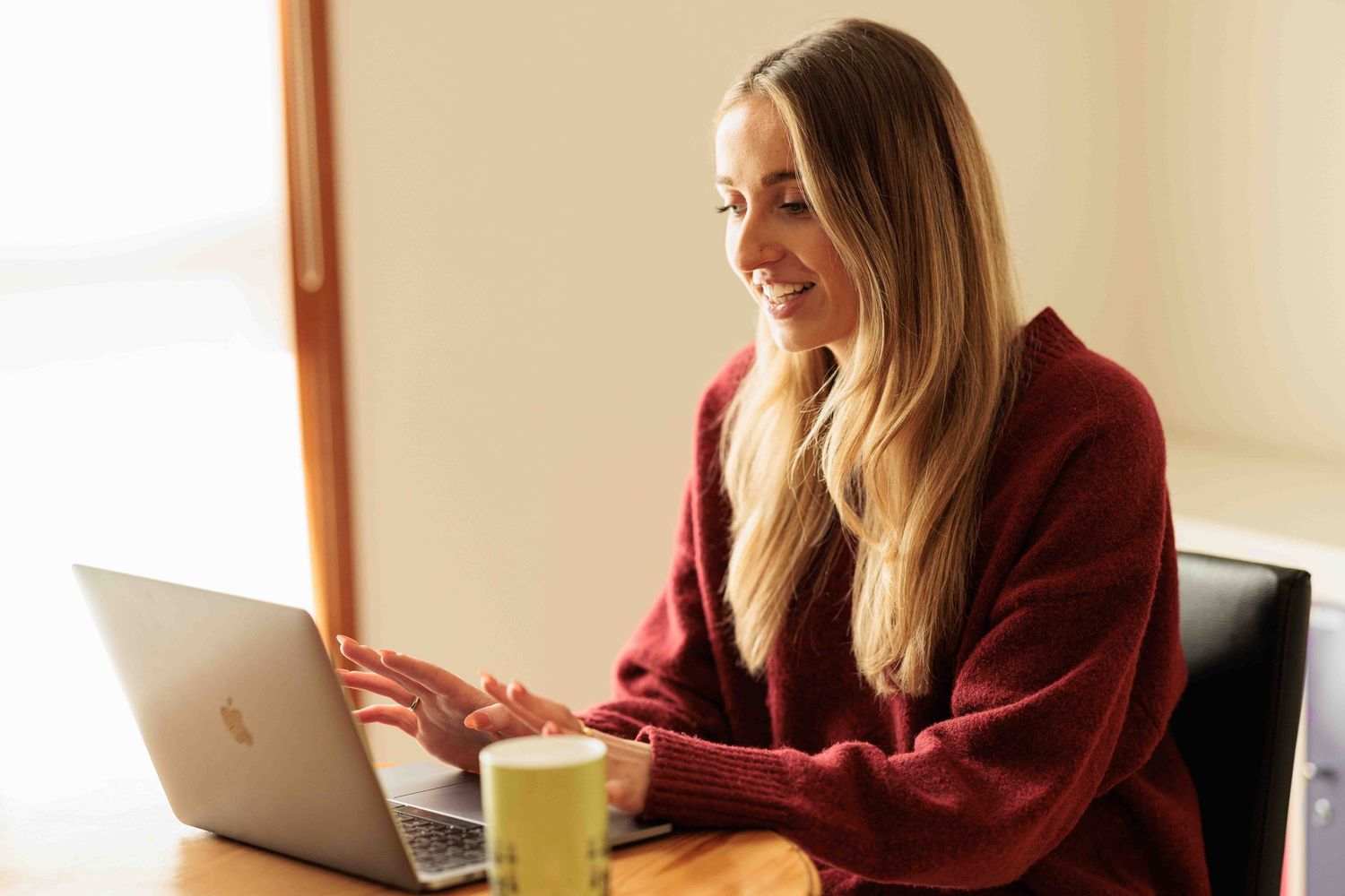 young woman smiling and working at a laptop
