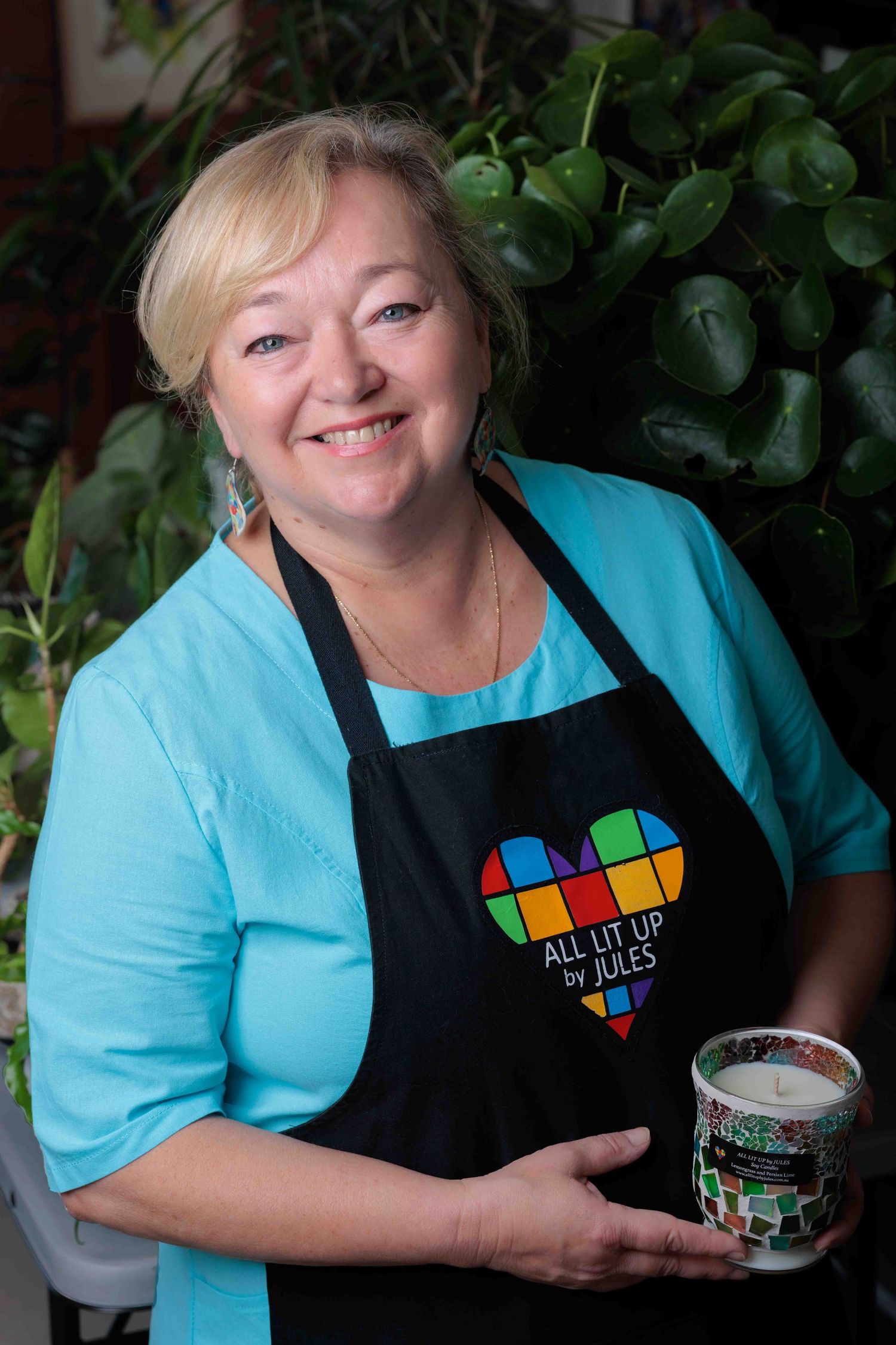 Woman smiling with blue dress and black apron with colourful logo