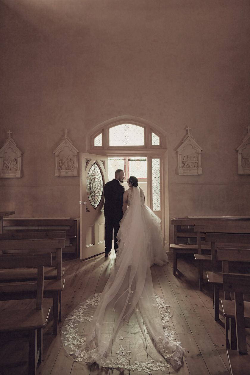 Bride and Groom leaving the chapel with dress flowing behind Micro wedding photography.