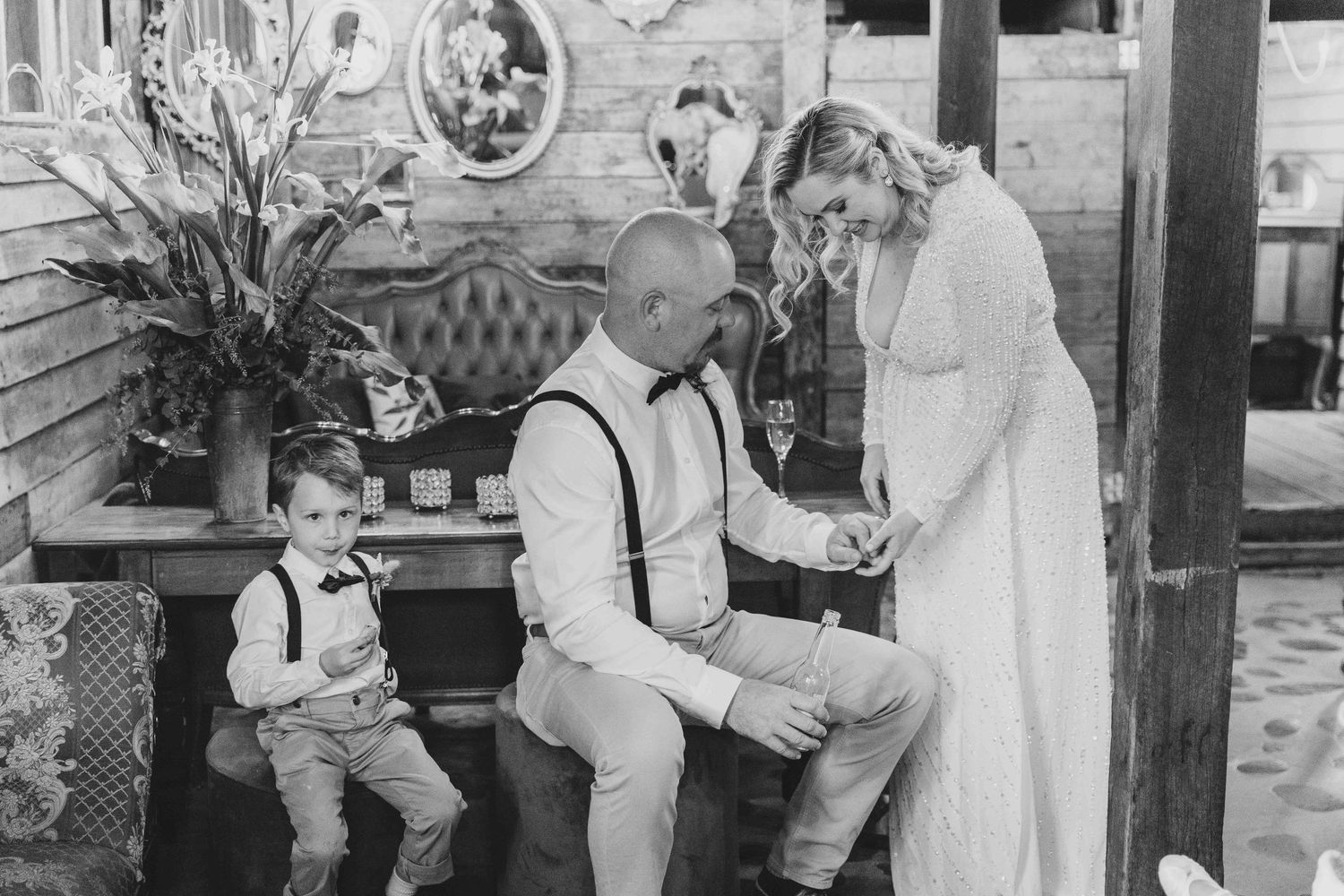 Just married couple look at their wedding rings while young son sits nearby.