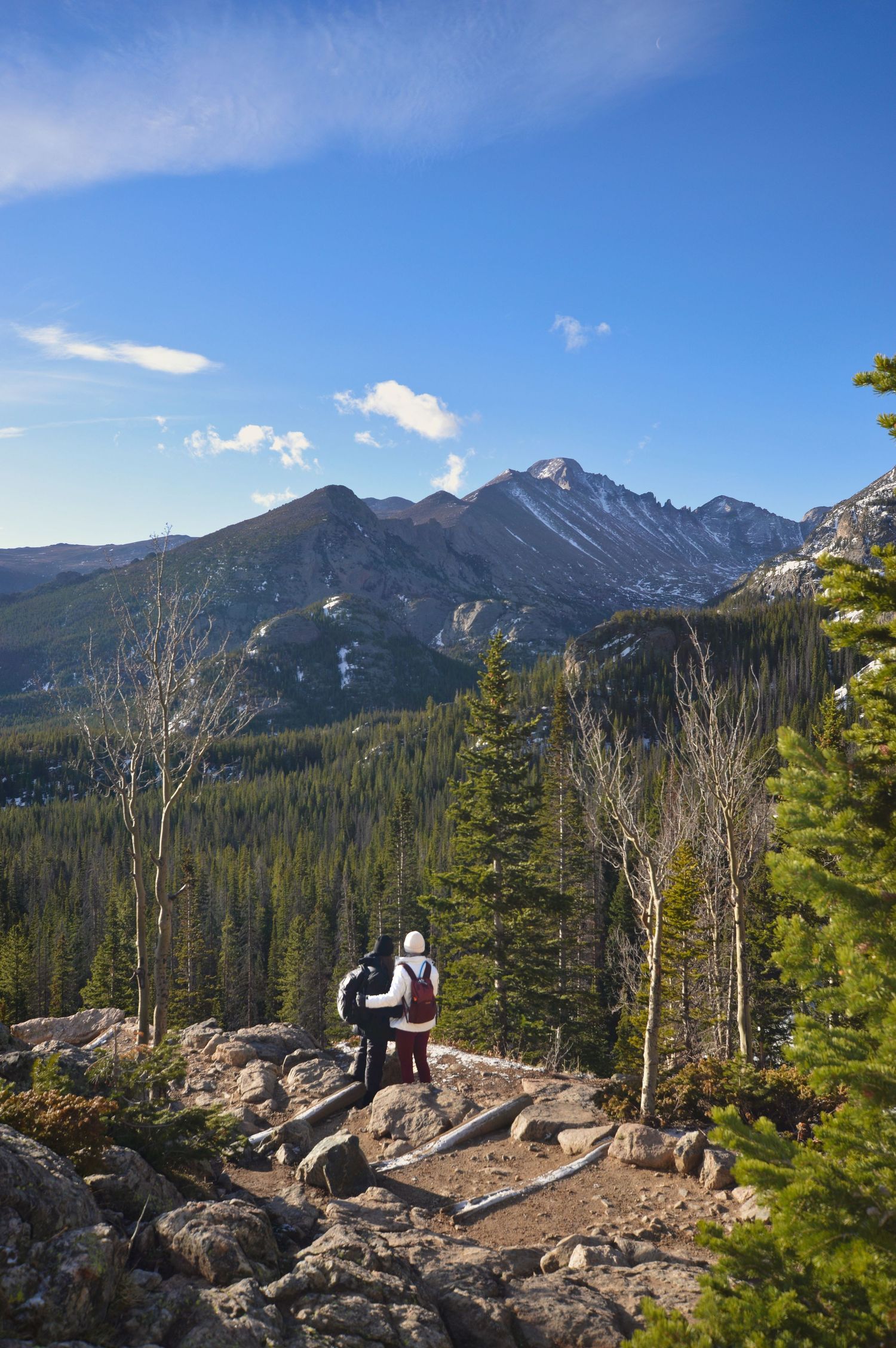 Couple pausing to take in the view of Longs Peak in the distance from the Dream Lake trail. The Rocky Mountain Proposal Photographer