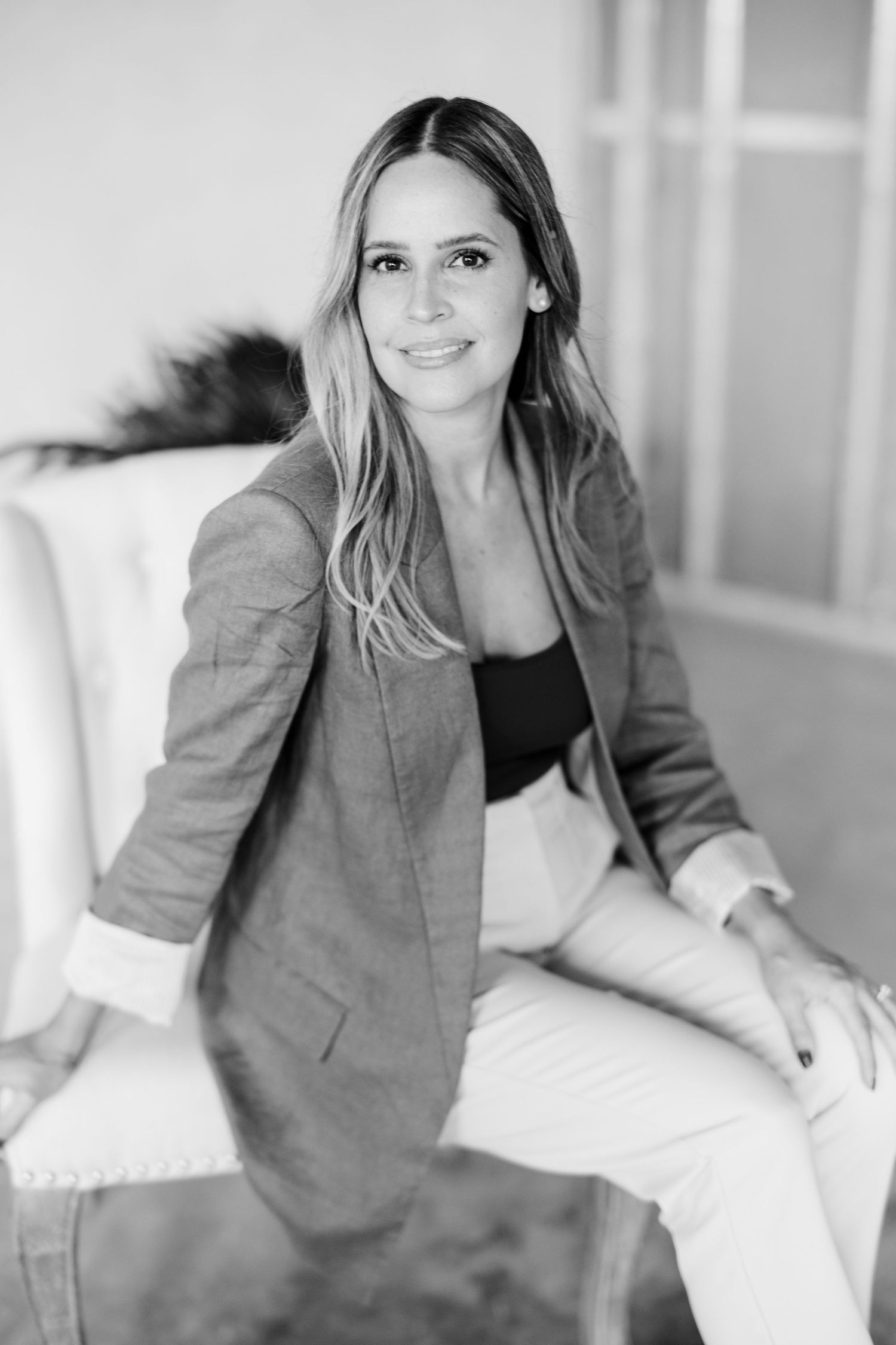 A woman in a gray coat sits on a couch.