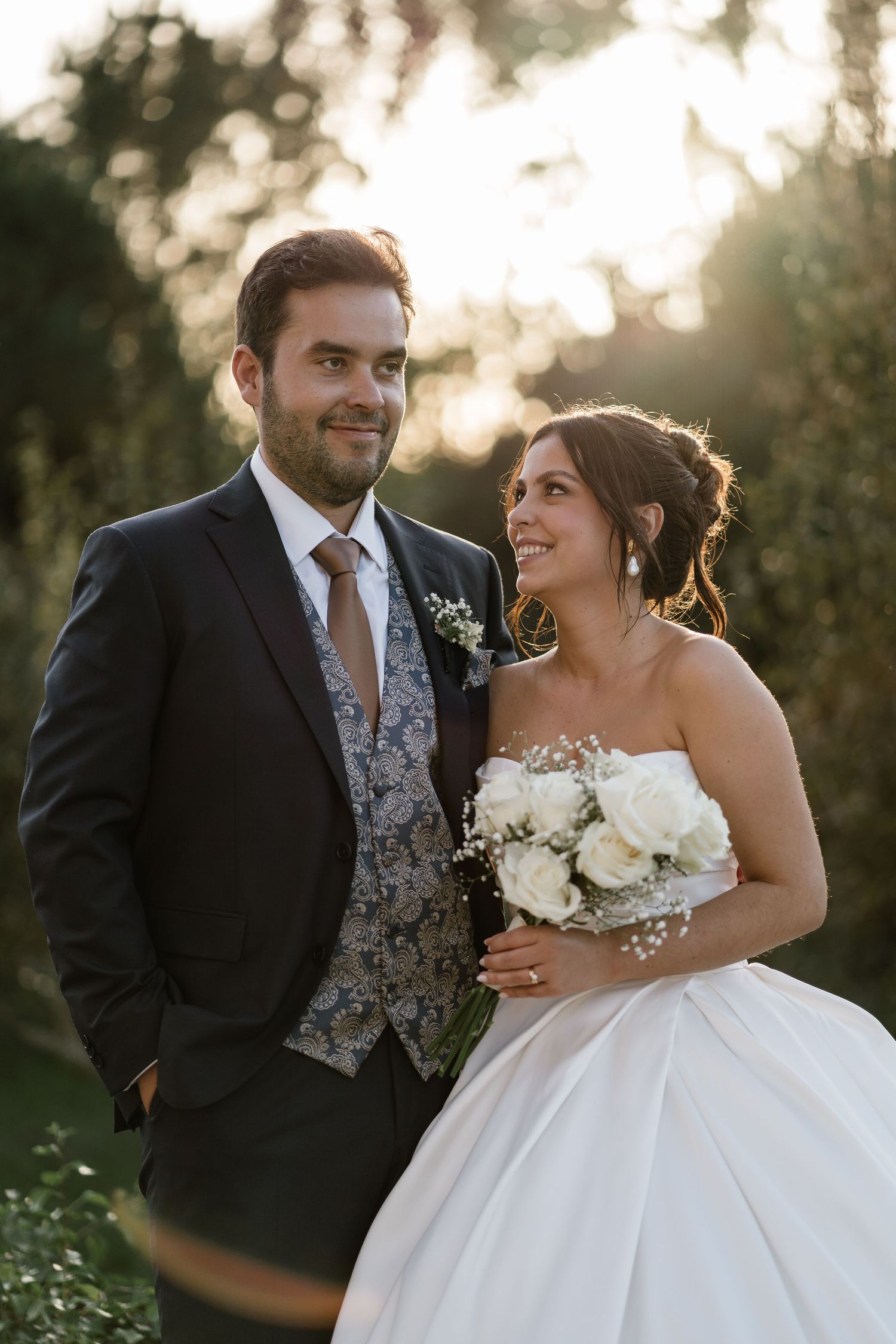 A wedding couple share an intimate moment at sunset in their formal attire.