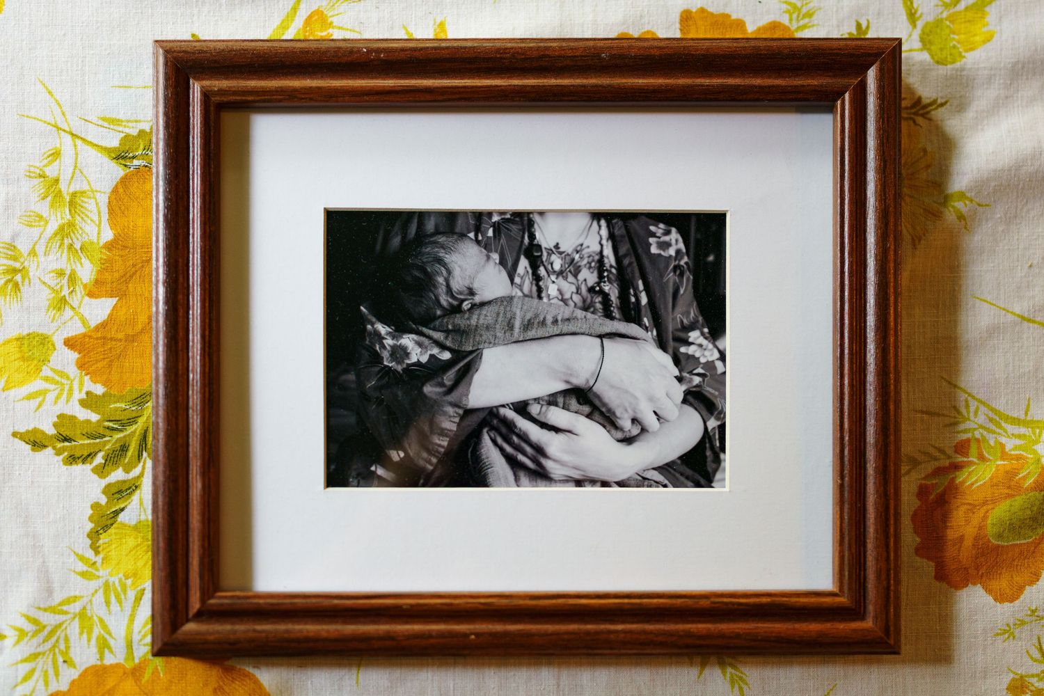 An abstract painting with swirling golden yellow brushstrokes and a brown wooden frame hangs on a white wall.