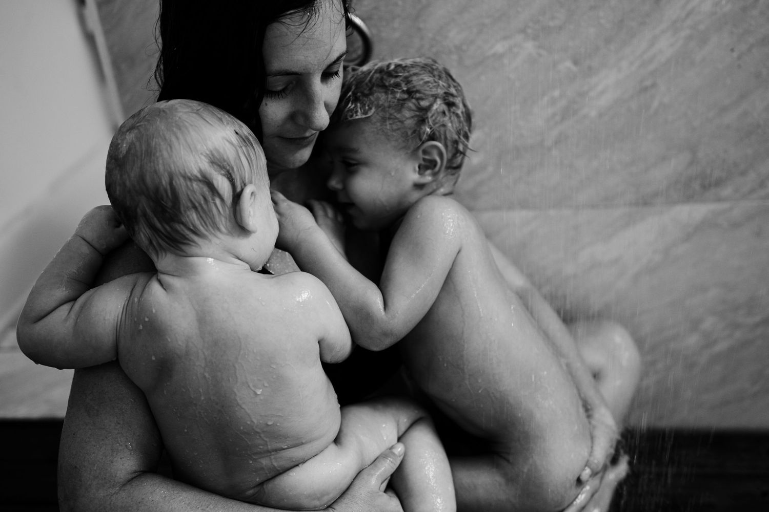 An intimate black and white photograph of mother and children. In home lifestyle photography done in New Orleans.