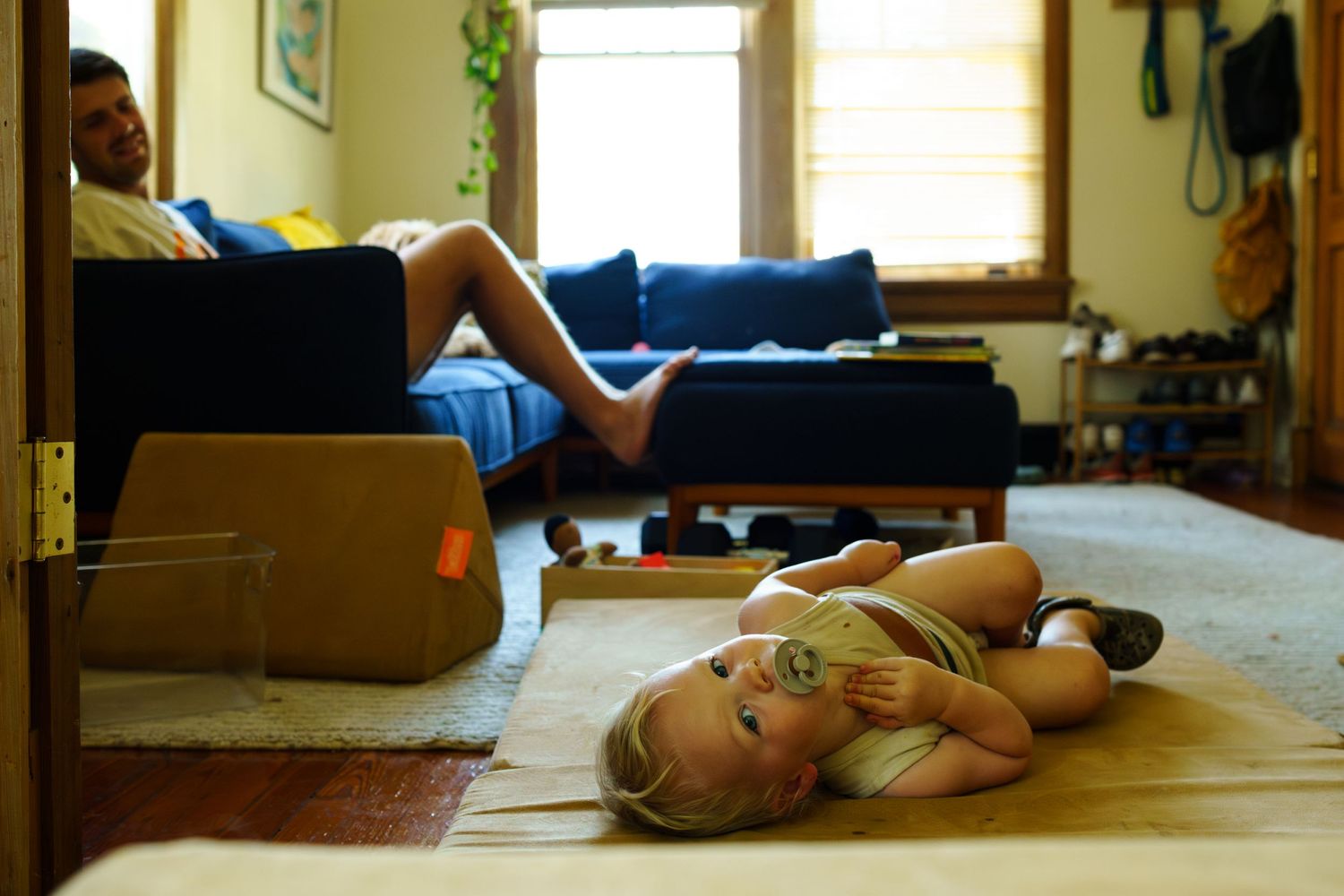 Documentary birth photography captures a quiet moment of rest and recovery in a sunlit room.
