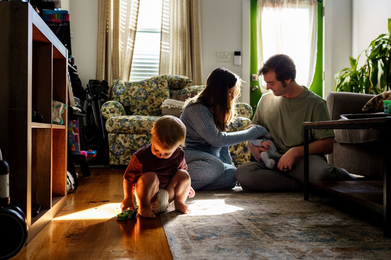 A family spends time together in their living room with sunlight streaming through the blinds.