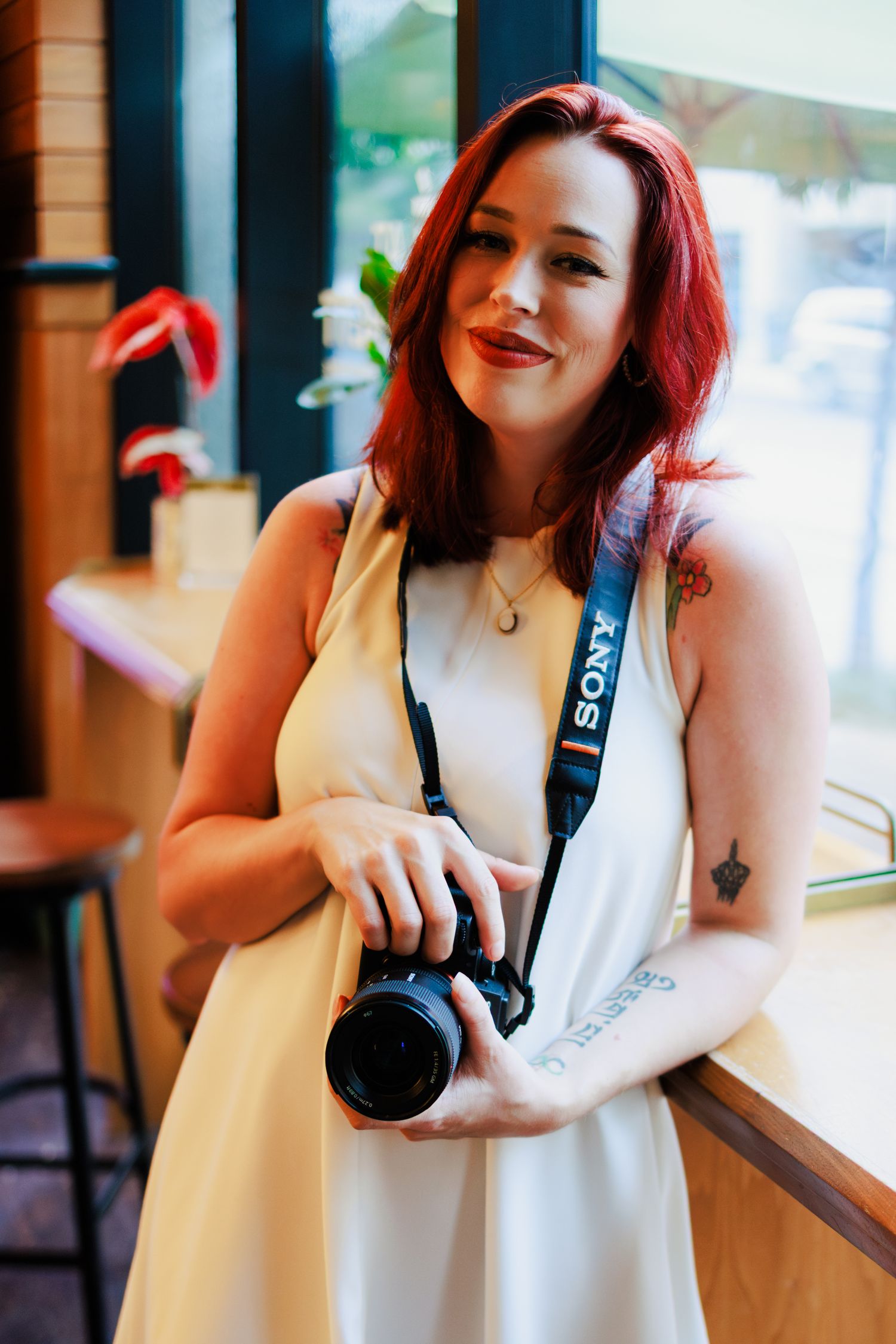 New Orleans birth photographer Autumn Hutton stands near a window holding her camera for a head shot.