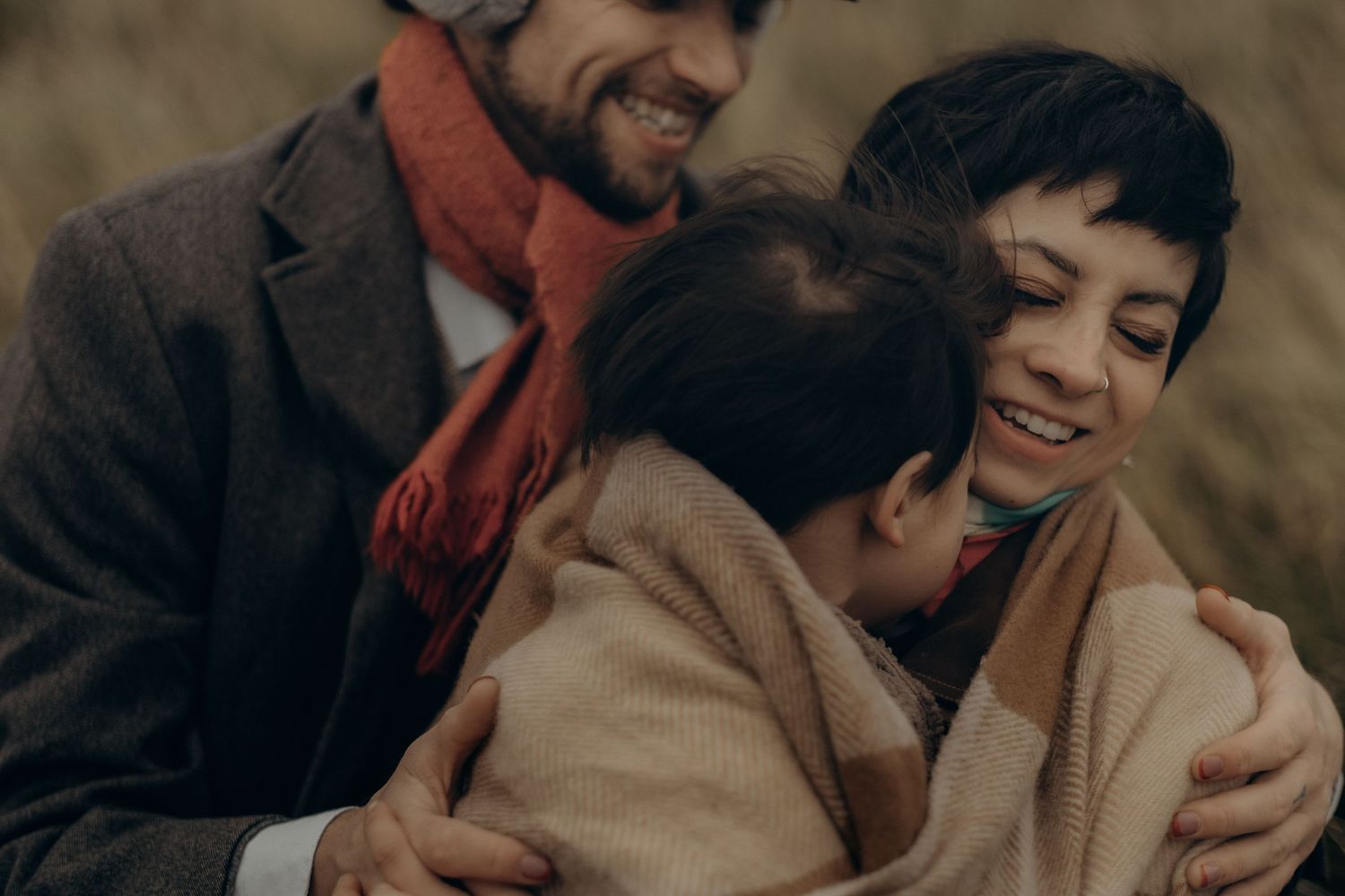 Family with little son wrapped in a blanket while being captured by family photographer in Stockholm with candid approach