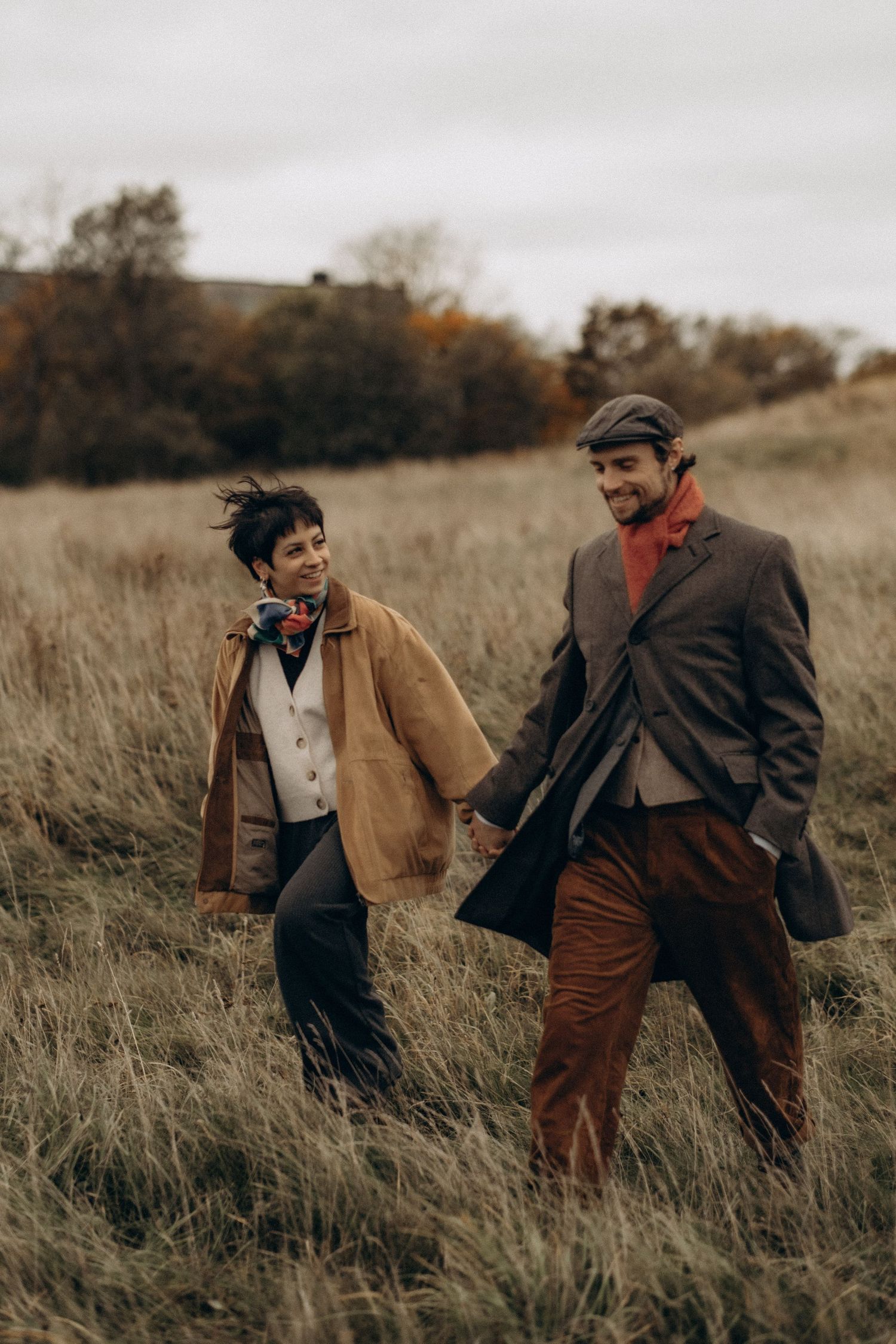 couple walking through fields holding hands during outdoor family photoshoot in October in Stockholm