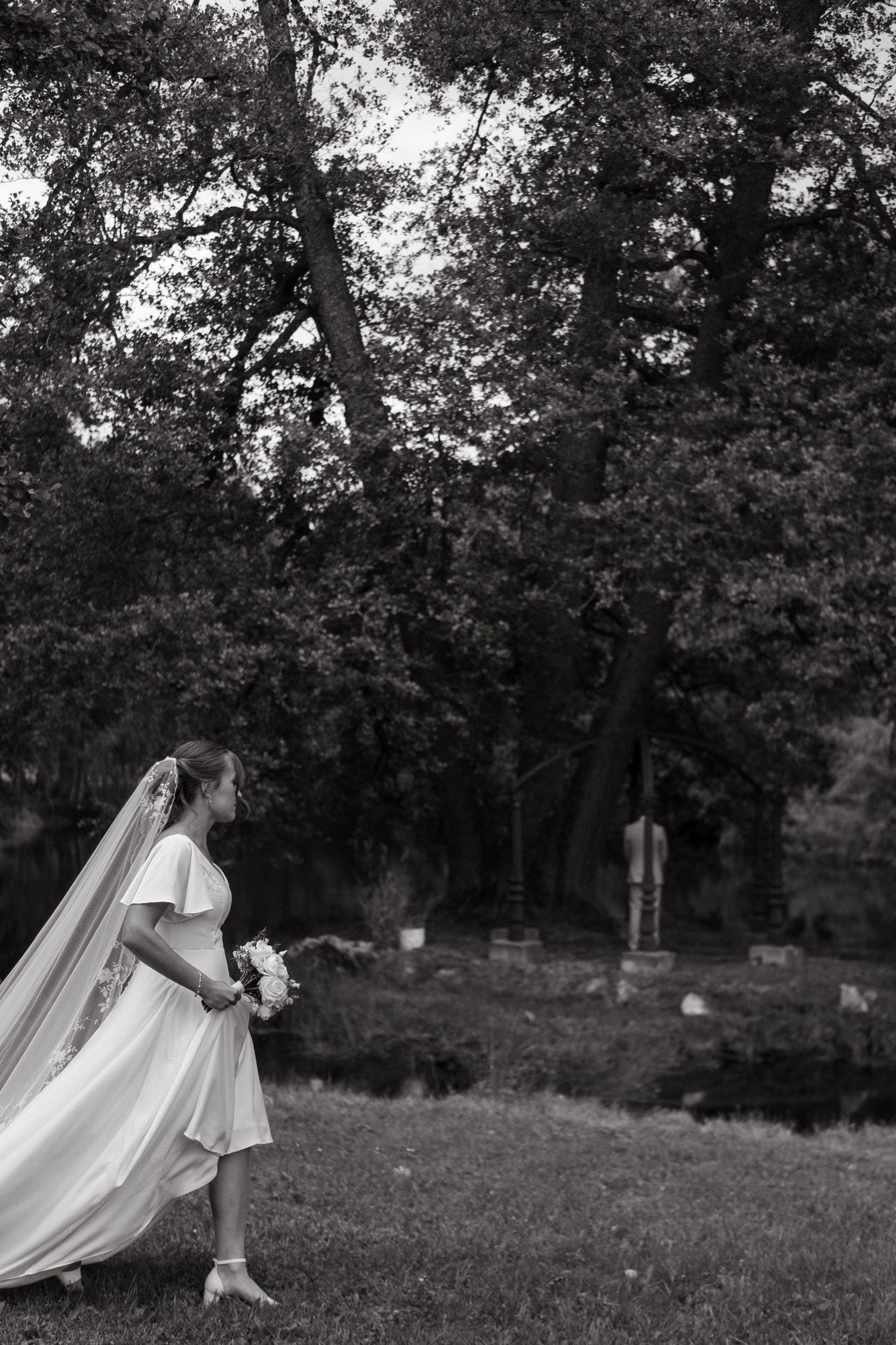 bride walking towards groom in rainy garden during naturally-looking wedding photoshoot in Stockholm