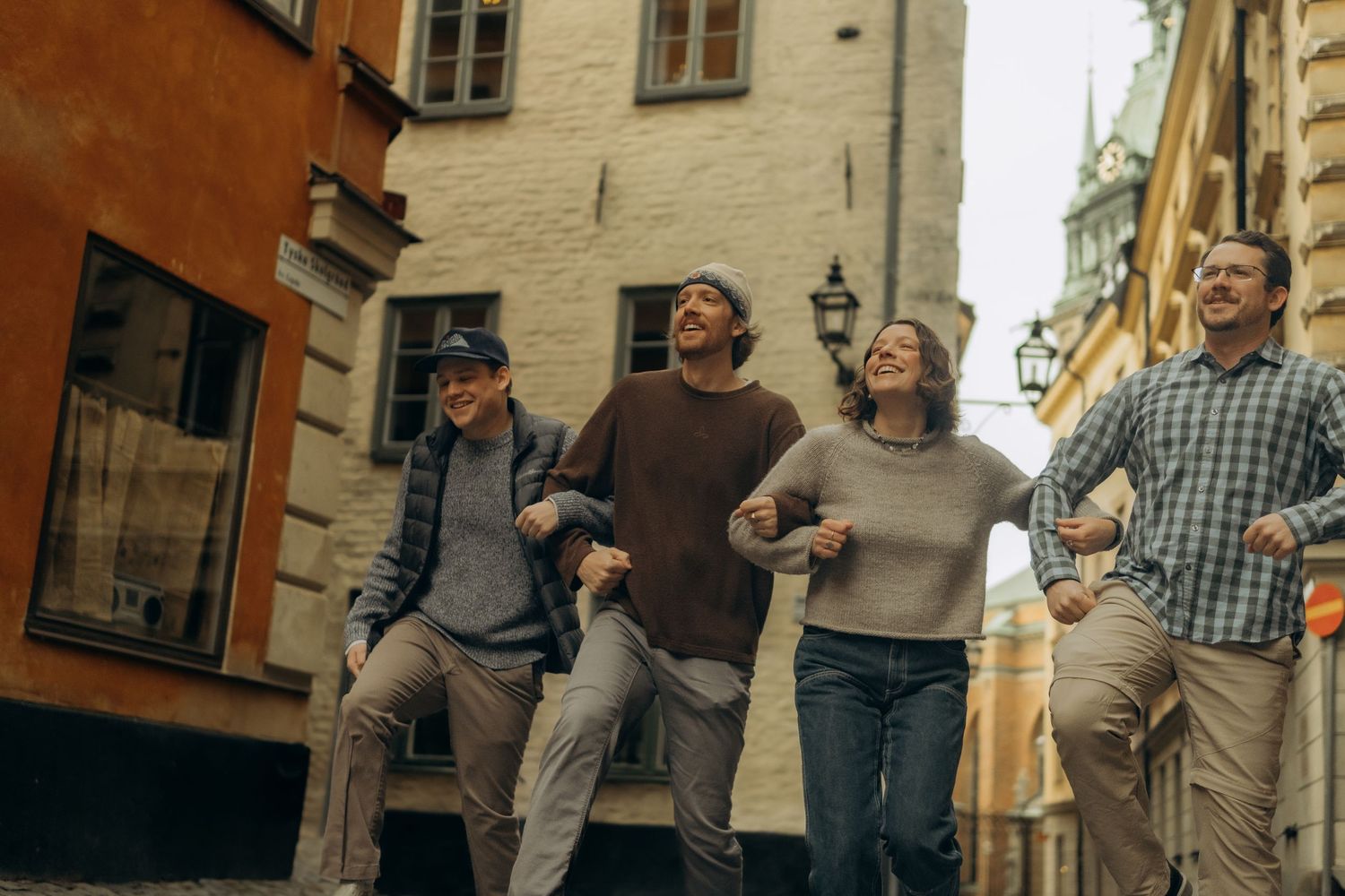group of adult kids hopping through Gamla Stan during family photoshoot in Stockholm during Christmas