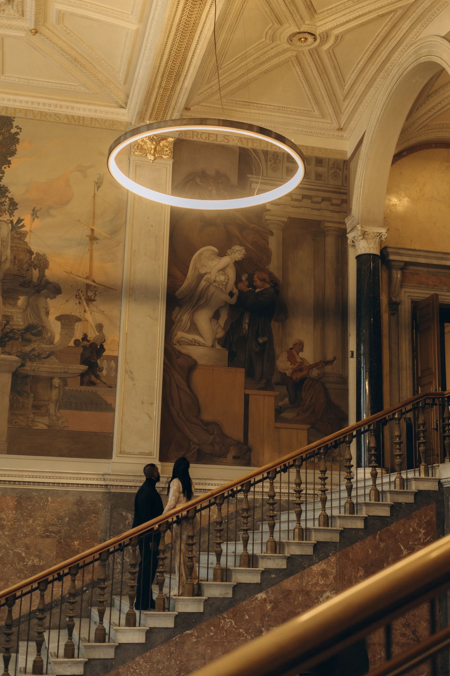 bride and groom standing on a staircase in a museum while being captured by cinematic wedding photographer in Stockholm
