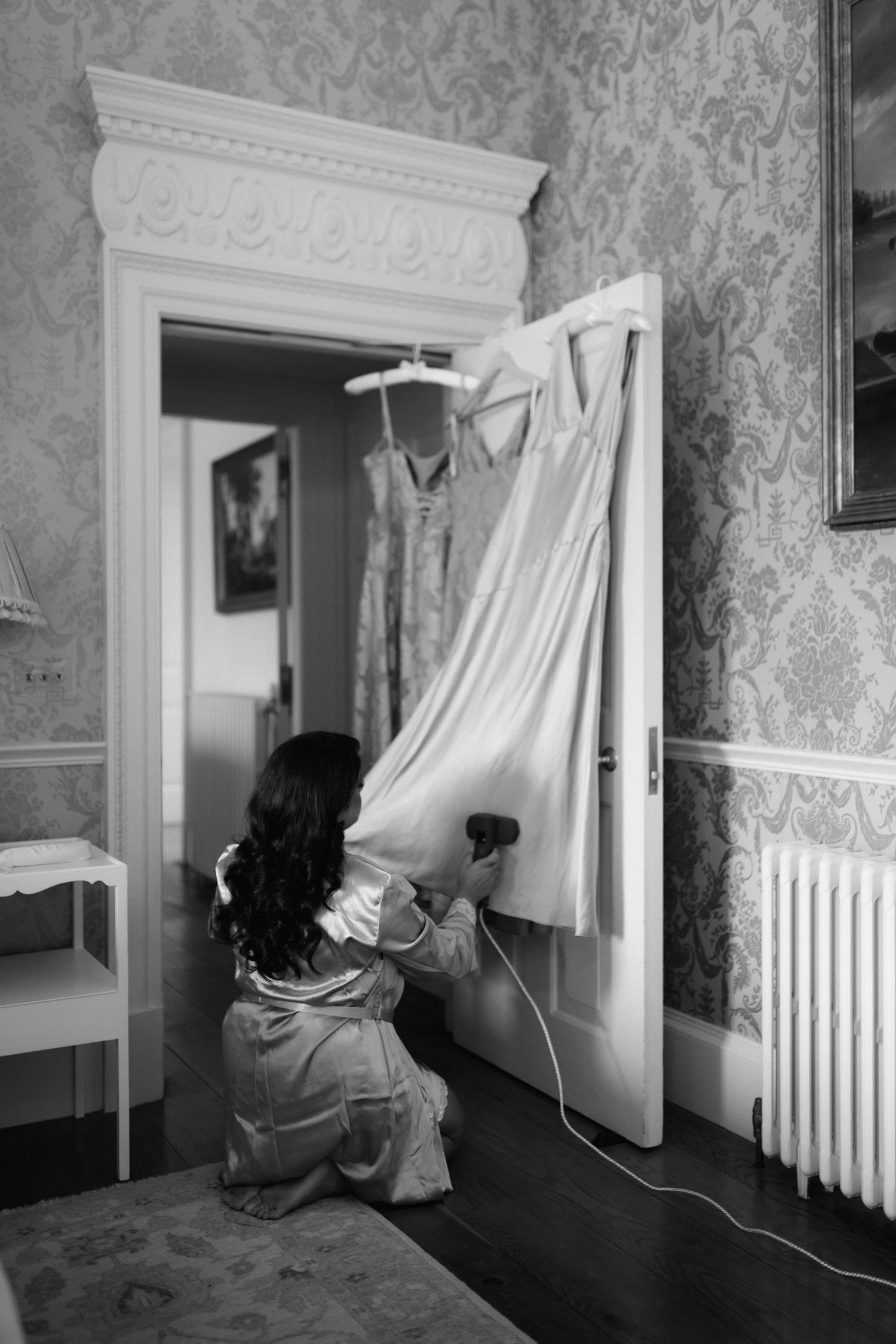 A sequence of black and white photos showing someone examining window curtains in a vintage room with patterned wallpaper.