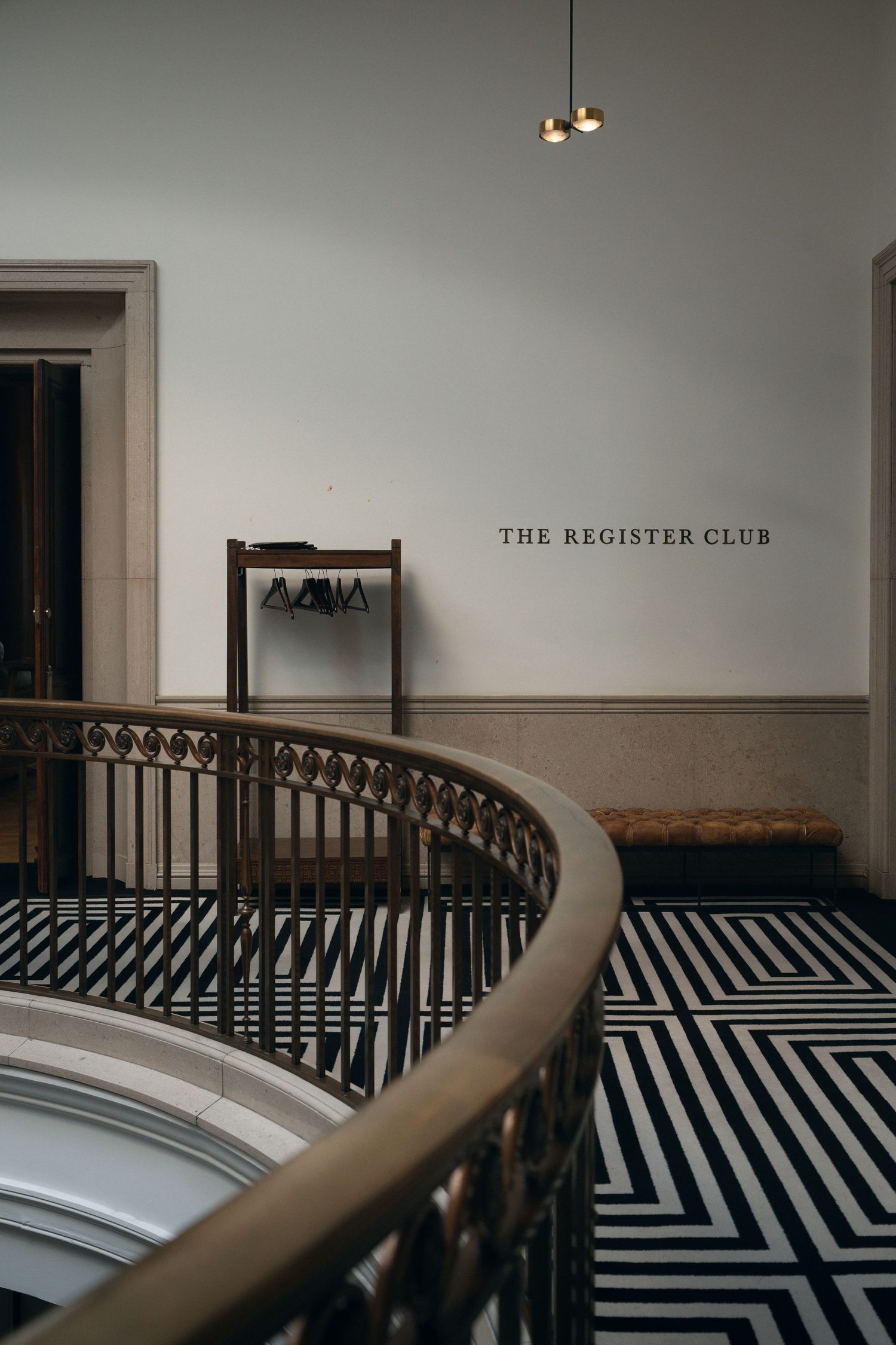 Art deco hallway with black and white geometric floor pattern and curved railing at The Register Club.