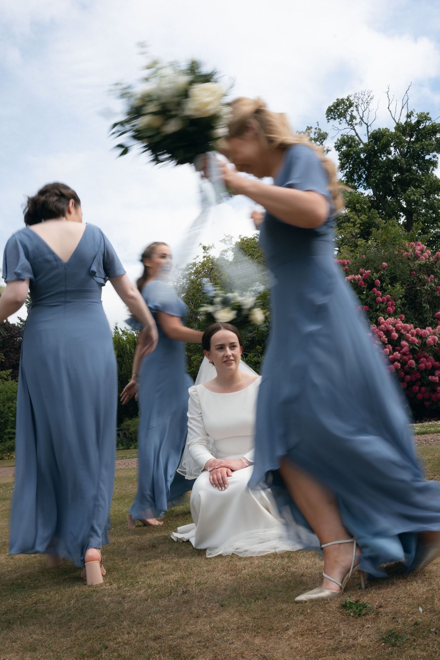 A sequence of motion photos capturing bridesmaids in blue dresses dancing and twirling outdoors on a grassy hill.