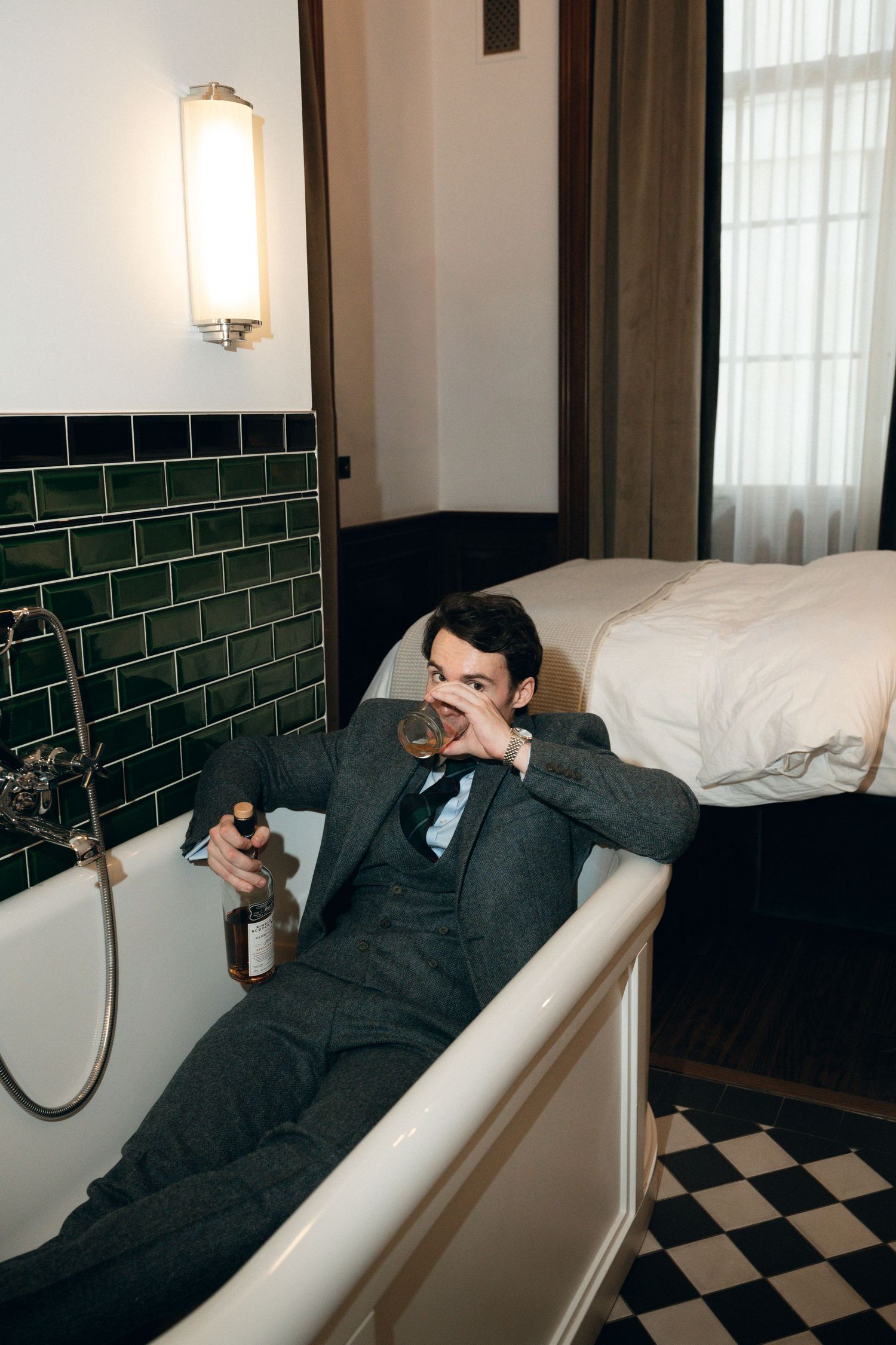 Interior of a luxurious bathroom with checkered floor and green subway tile walls.