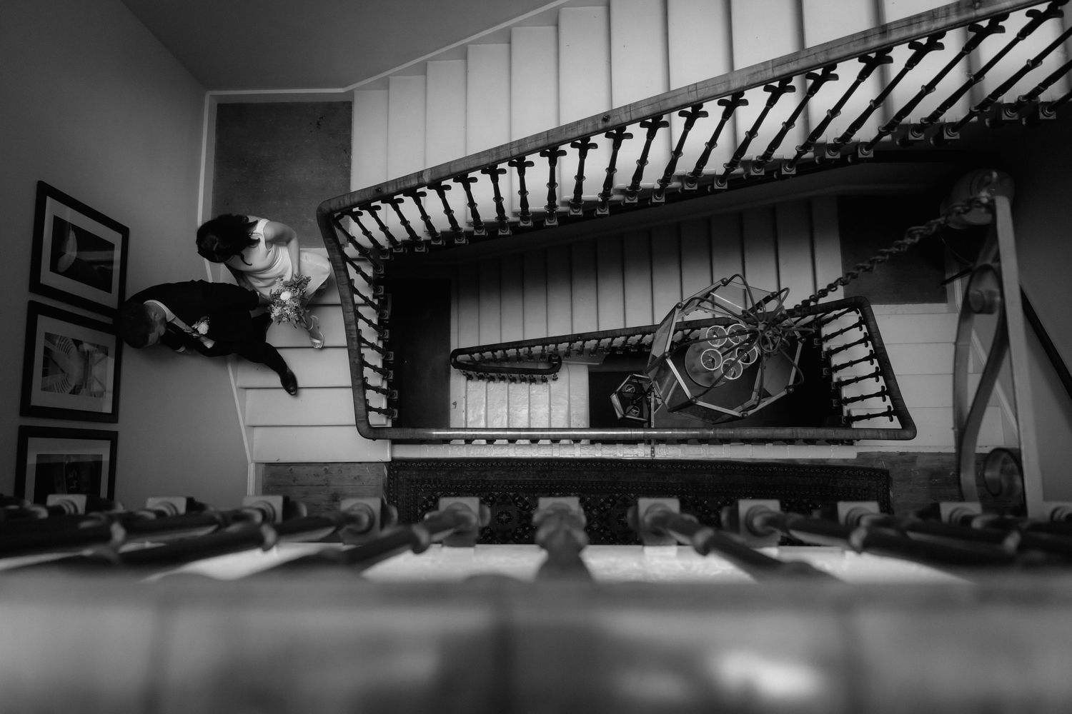 A vintage bicycle hangs on a stairwell wall in black and white, viewed from a unique low angle perspective.