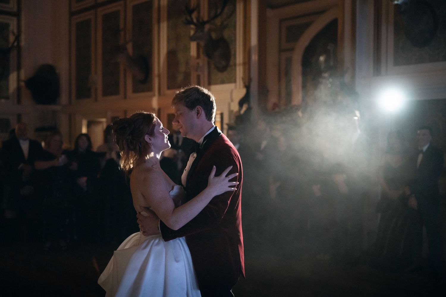 A couple shares their first dance at a wedding reception with dramatic lighting and fog effects on the dance floor.