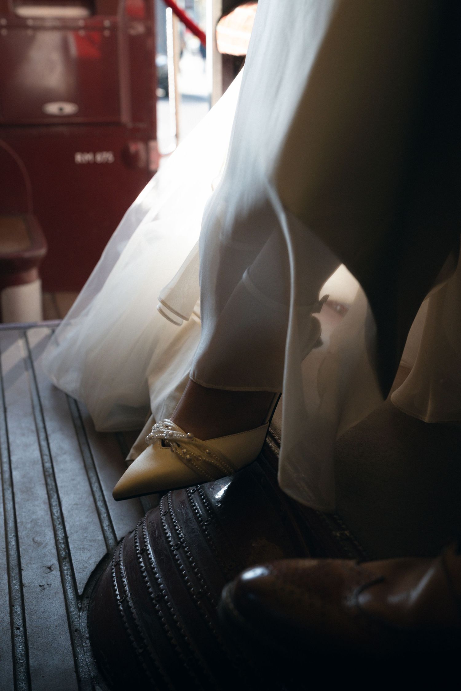 White wedding dress and shoes photographed in dramatic lighting against dark wooden floorboards.