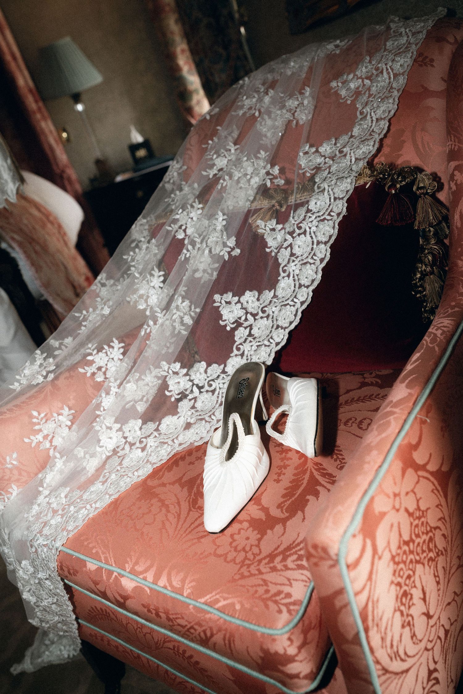 White lace fabric drapes elegantly over a pink damask upholstered couch or chair surface.