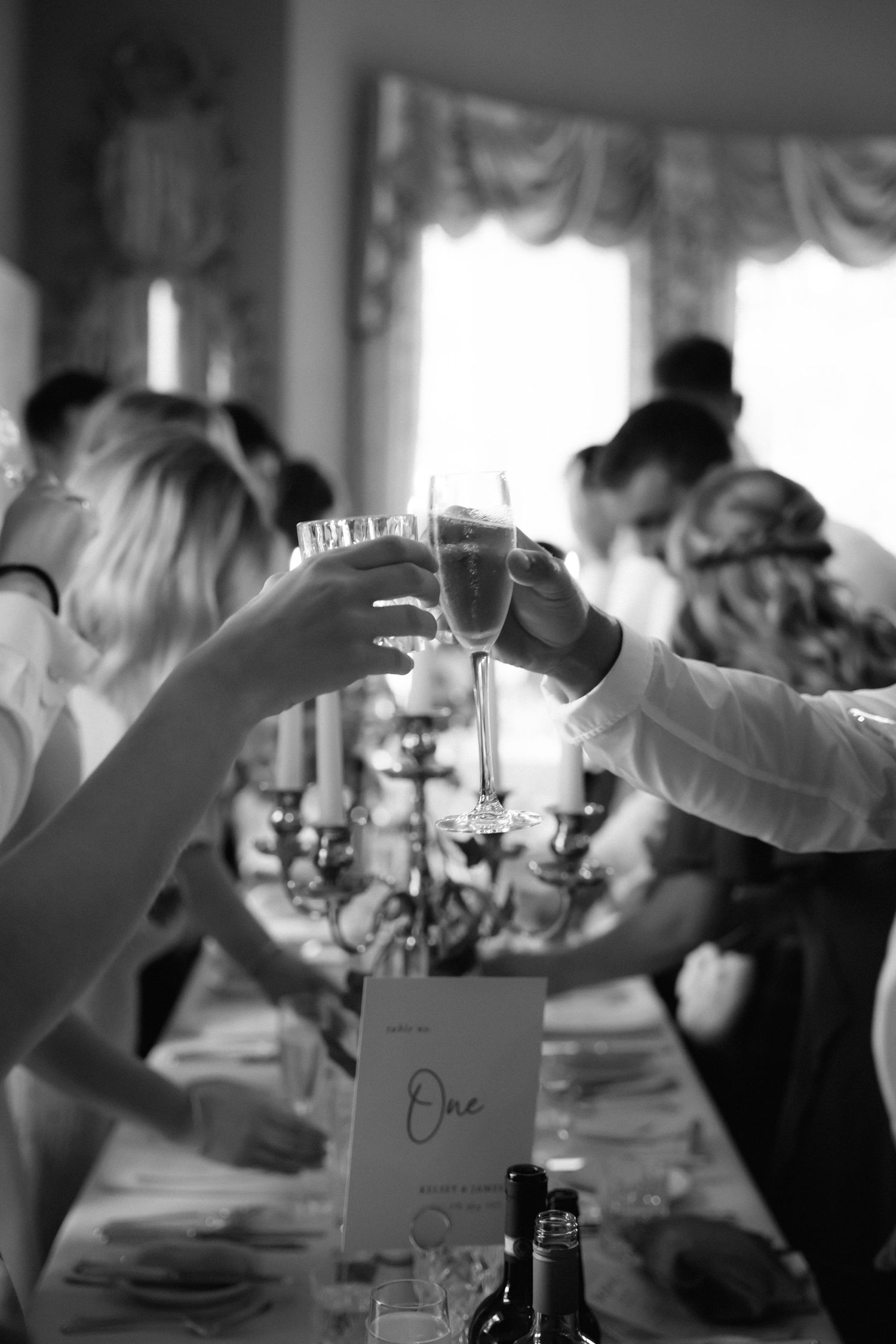 Champagne glasses being raised in a toast during an elegant indoor celebration.
