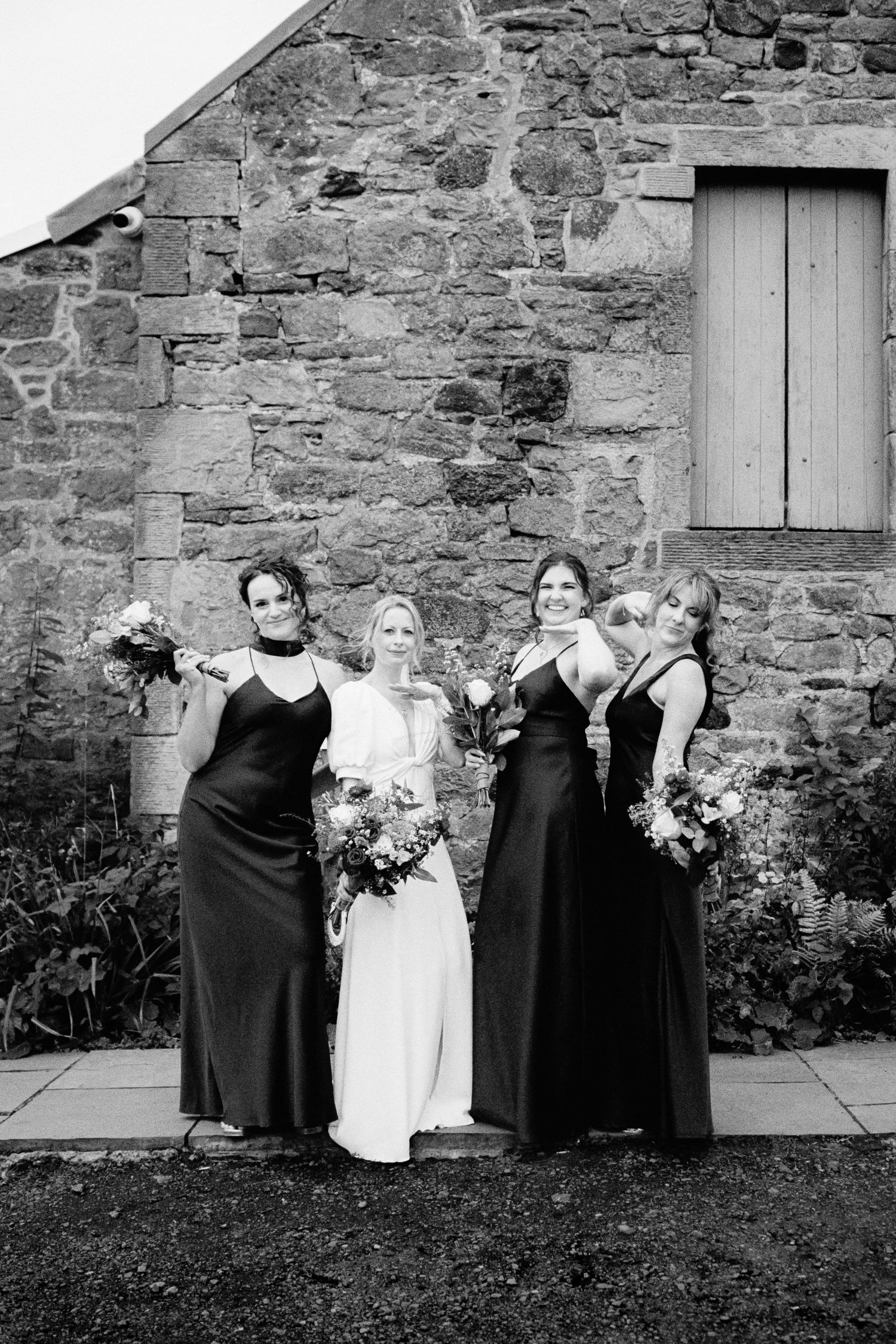 Black and white wedding party photos in sequence against a rustic stone wall and garden setting.