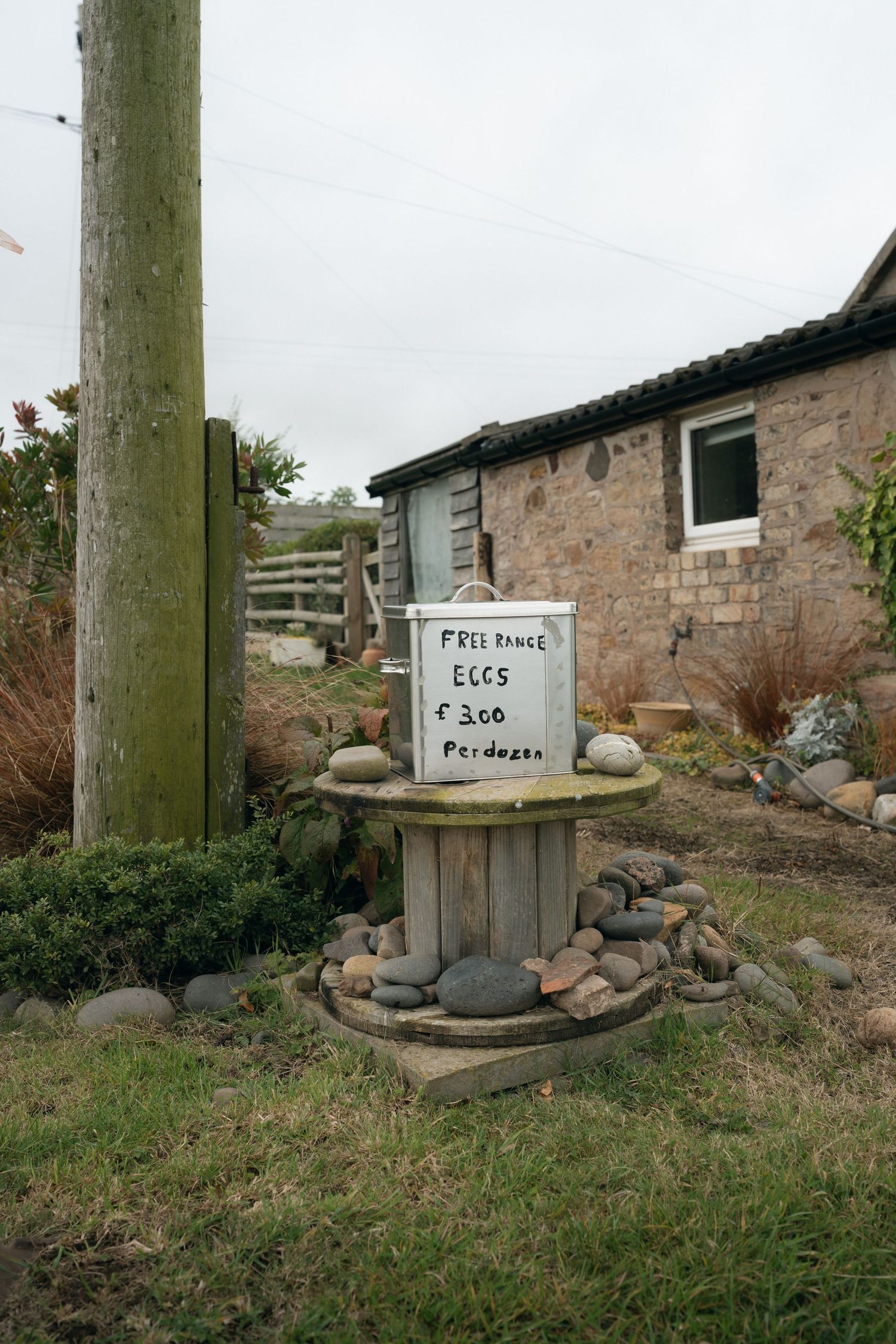 A series of rustic wooden signs with text mounted on weathered posts in a grassy rural setting.