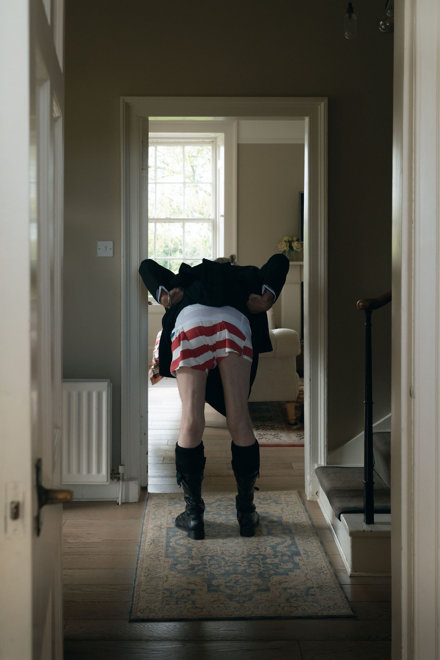 Three connected hallway views show a person bending down in dark clothing against white walls and carpet.