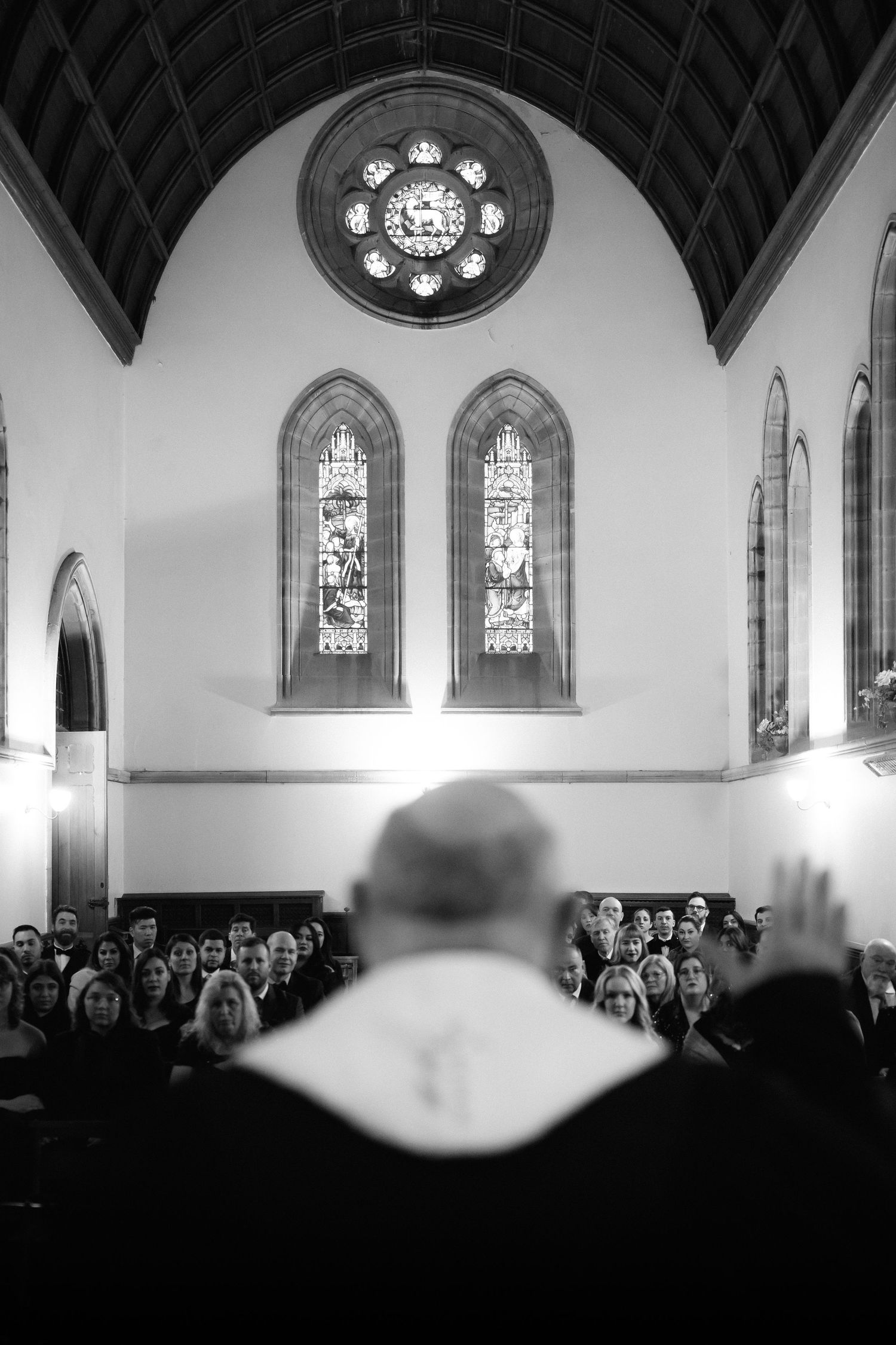 Black and white panoramic view of a church interior with gothic arches, stained glass windows, and a congregation gathering.