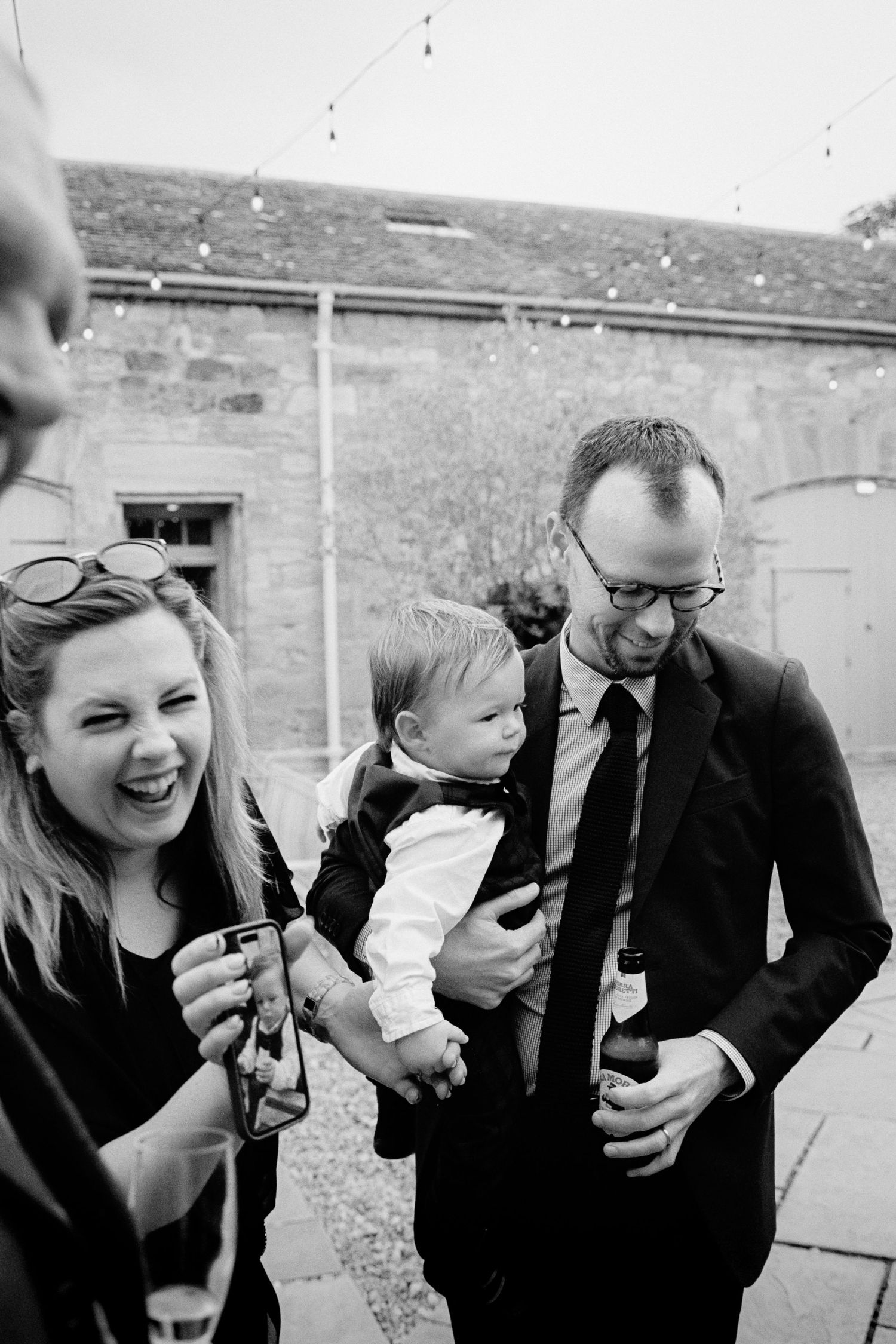 A sequence of black and white photos showing people laughing and sharing joyful moments together outdoors.