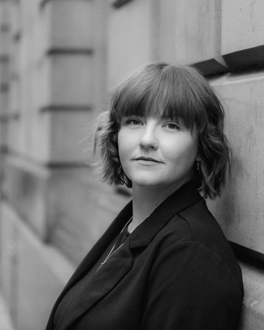 Black and white portrait showcasing dramatic side lighting and contrasting shadows against a textured wall.